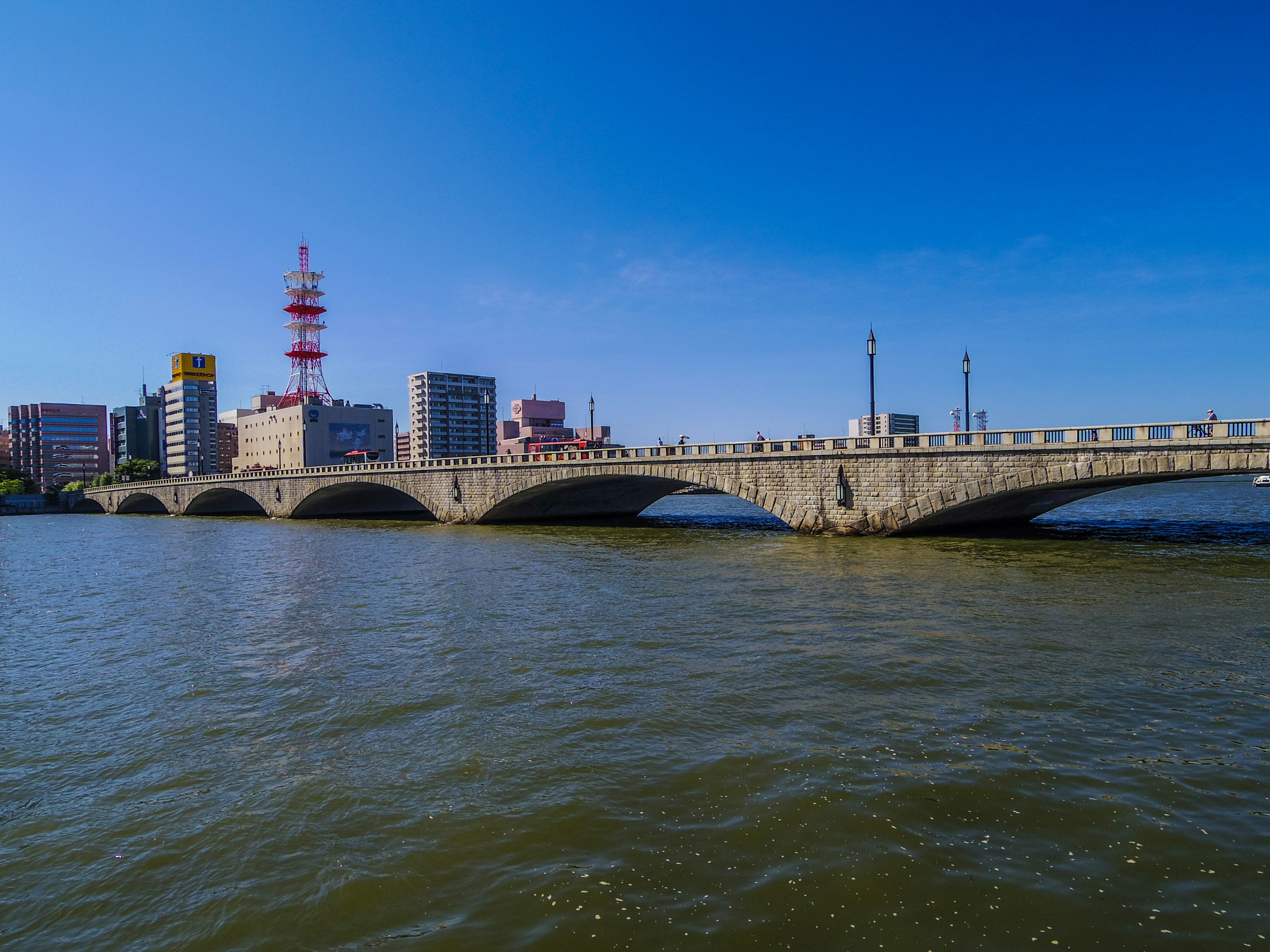 Puente sobre el agua con el horizonte de la ciudad y torre de telecomunicaciones