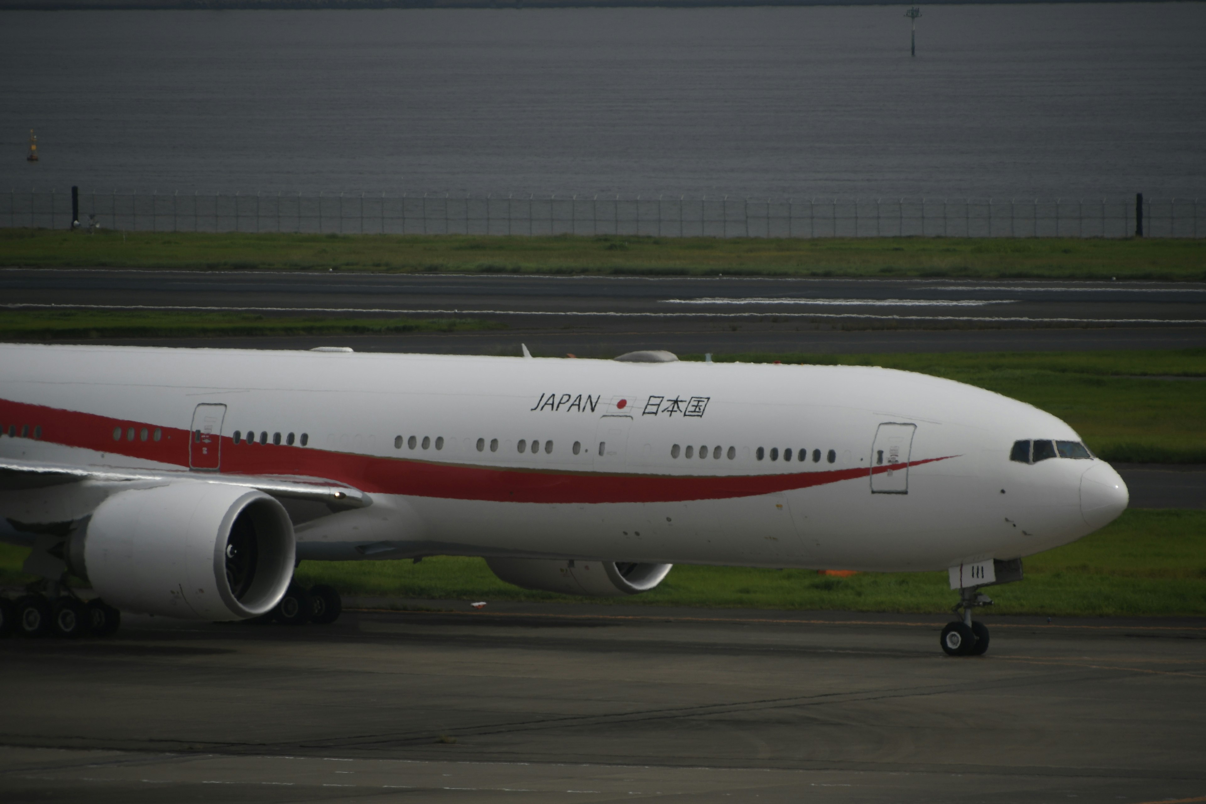 Airplane with white body and red stripe parked on the runway