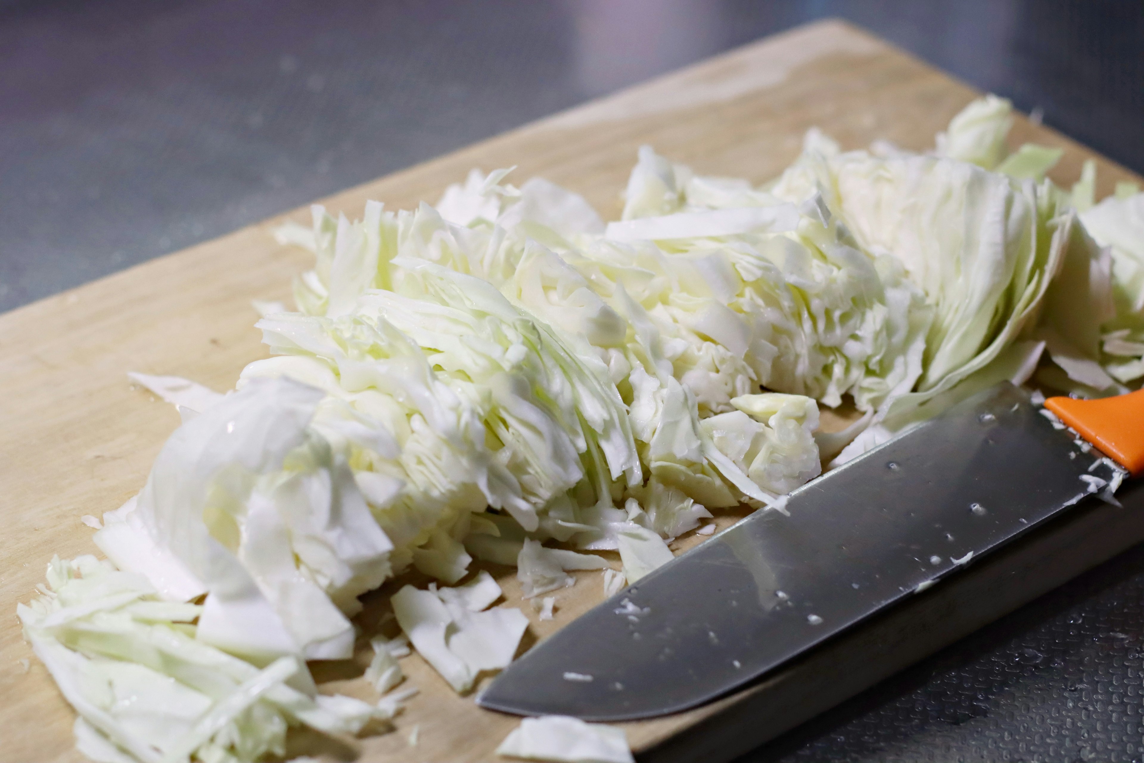 Chopped cabbage with a knife on a wooden cutting board