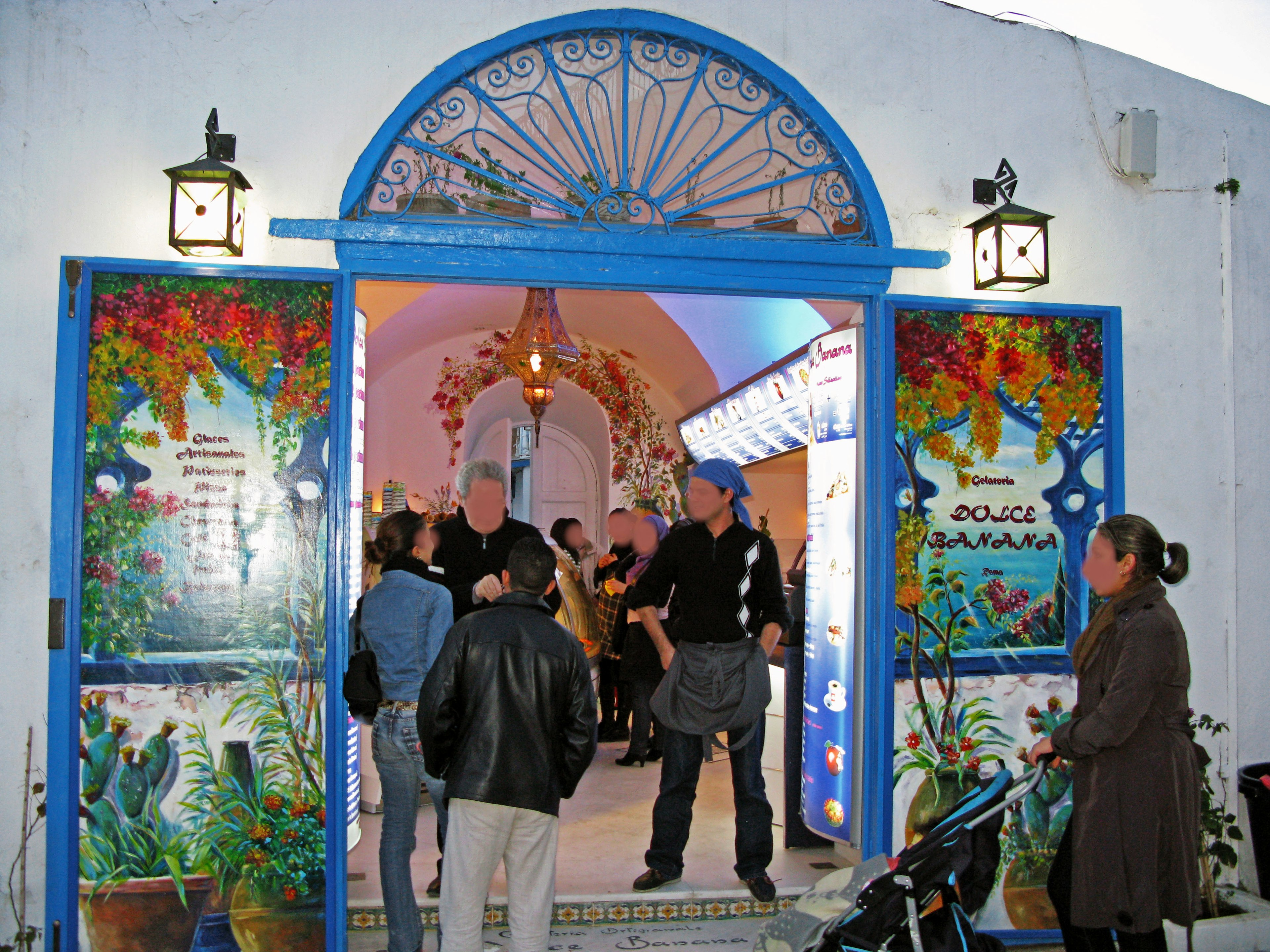 People gathered at the entrance with blue doors and colorful murals