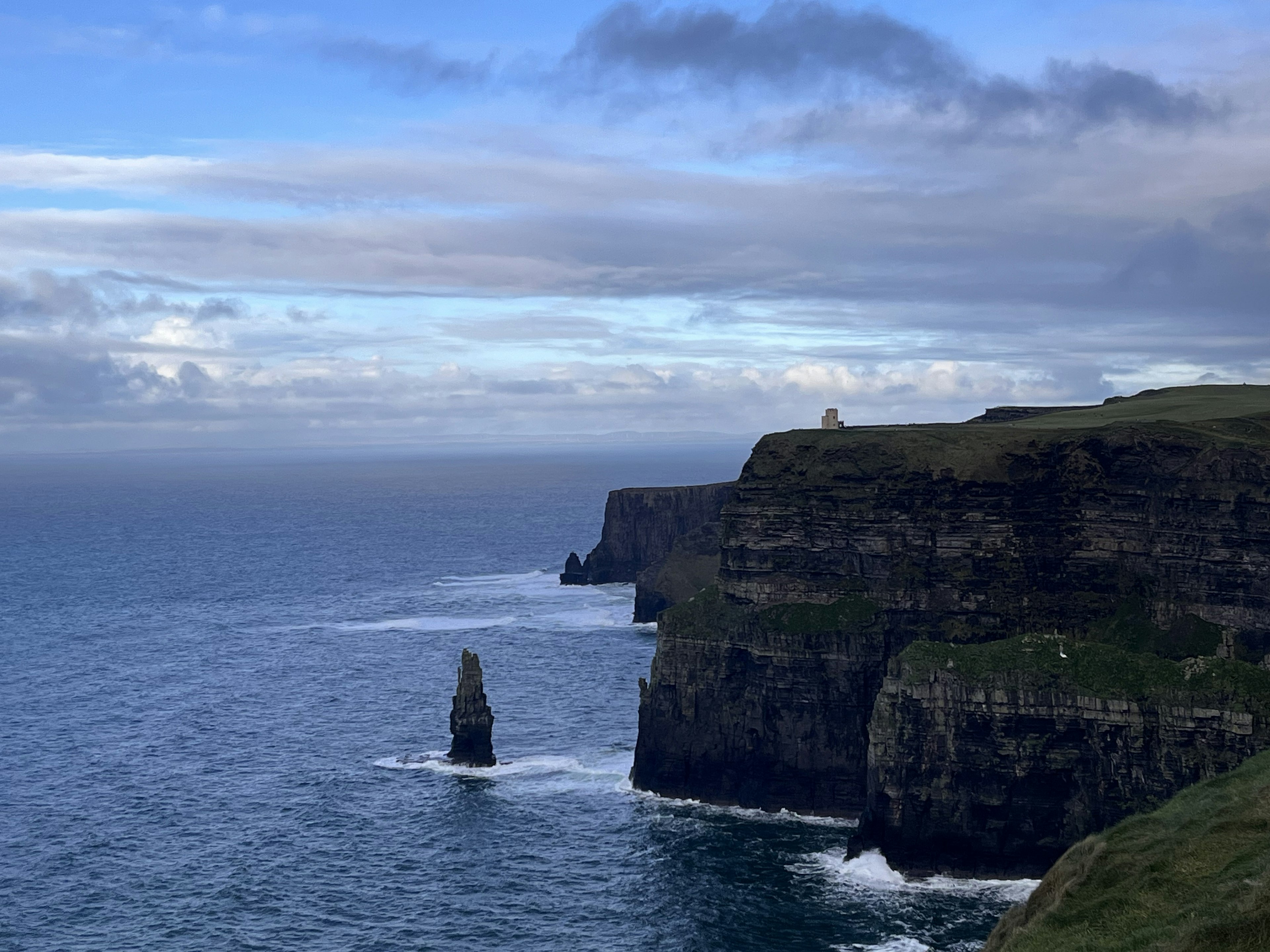 Côte pittoresque avec des falaises et un océan bleu avec un phare au loin