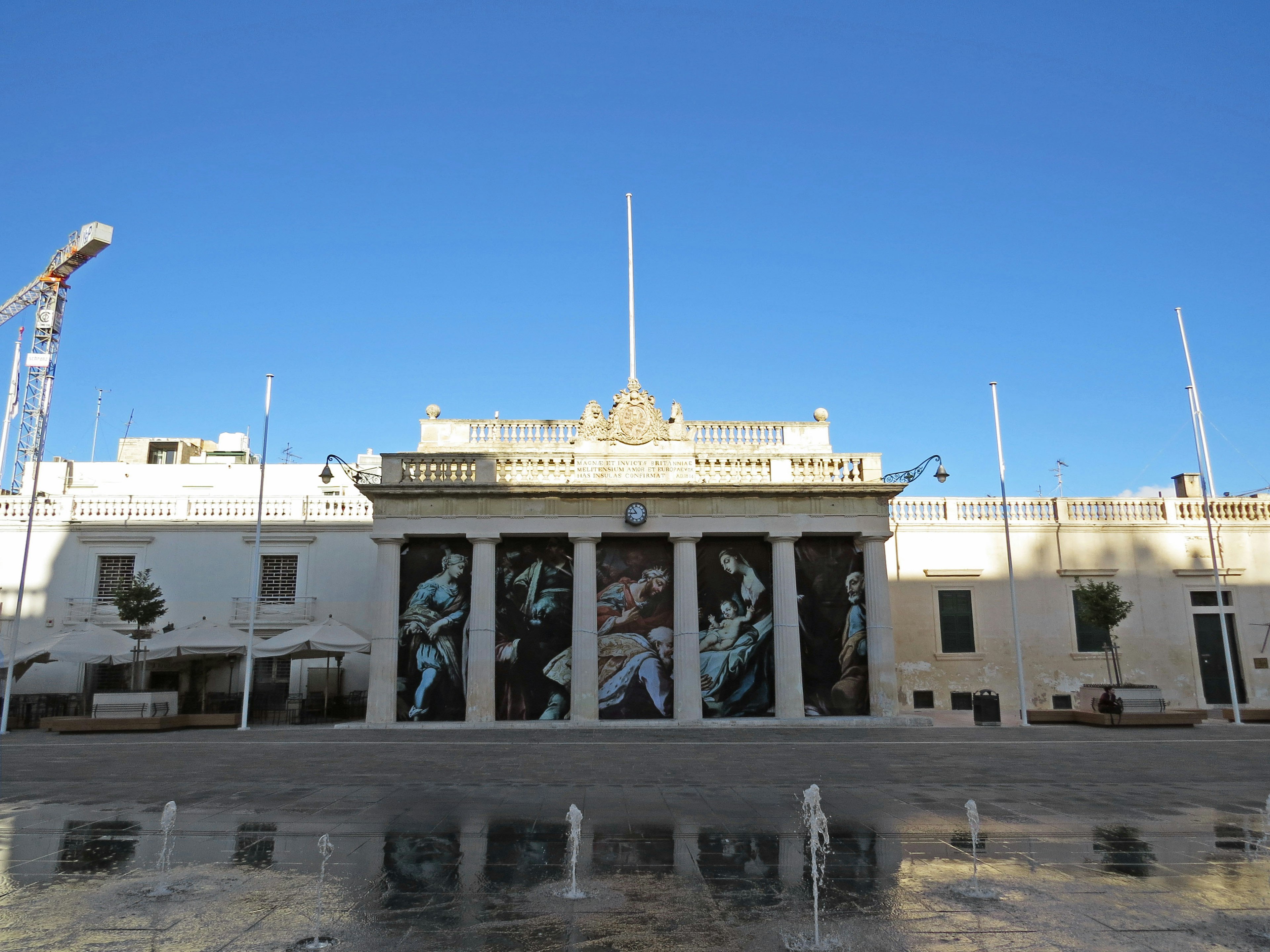 Edificio bianco con grande opera d'arte sulla facciata e cielo blu chiaro