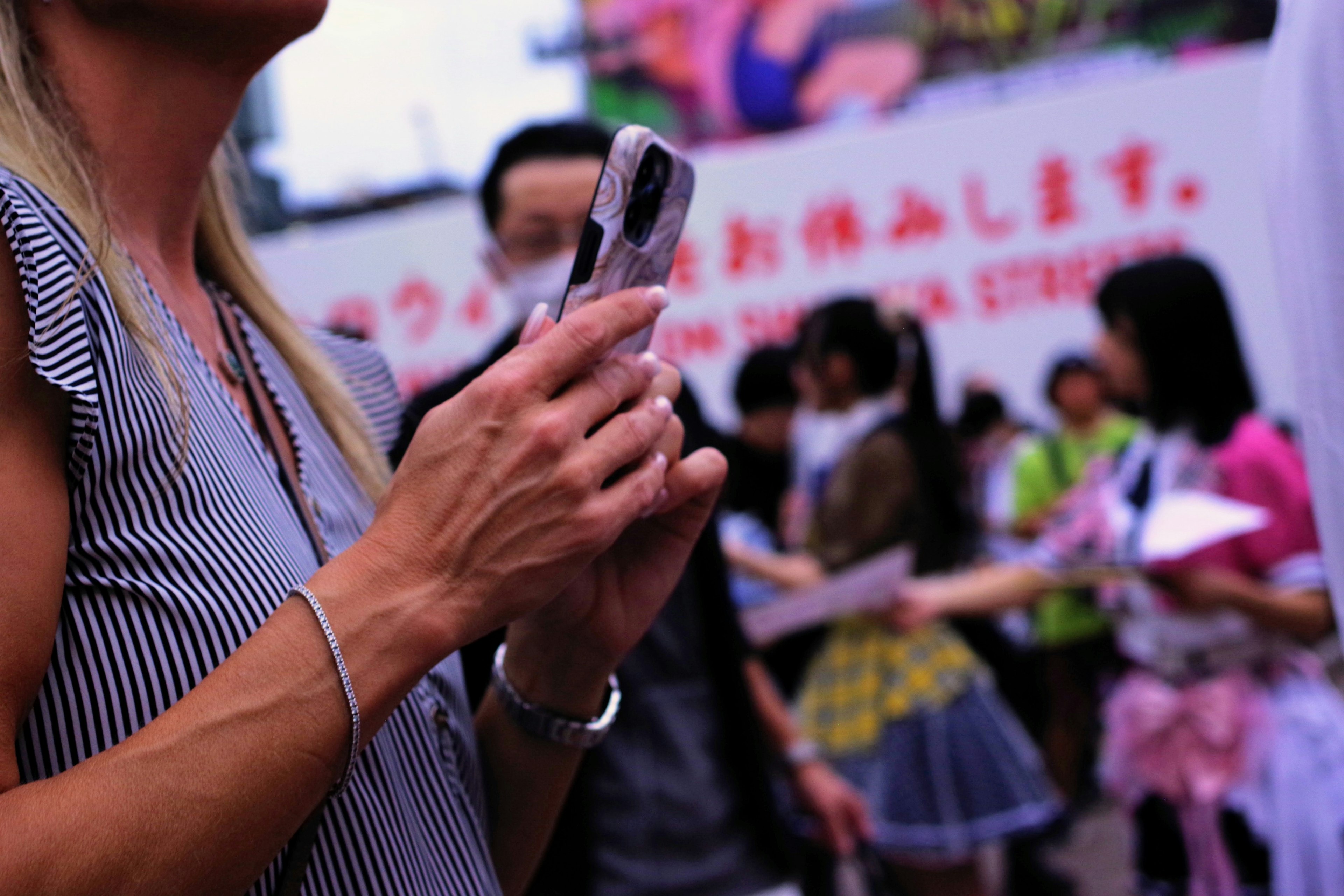 Una donna con uno smartphone in mano e una folla di persone sullo sfondo