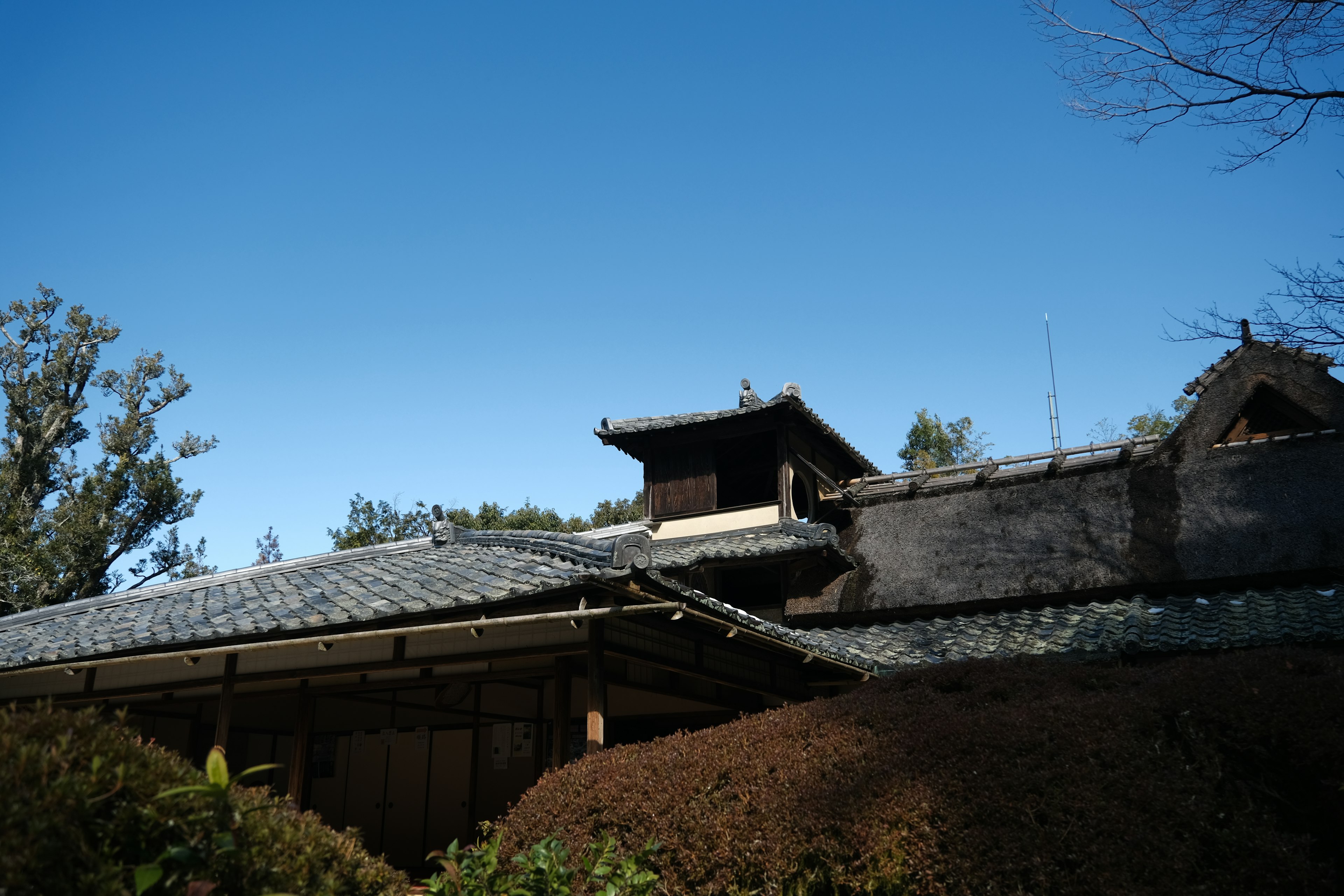 Atap rumah tradisional Jepang di bawah langit biru yang cerah