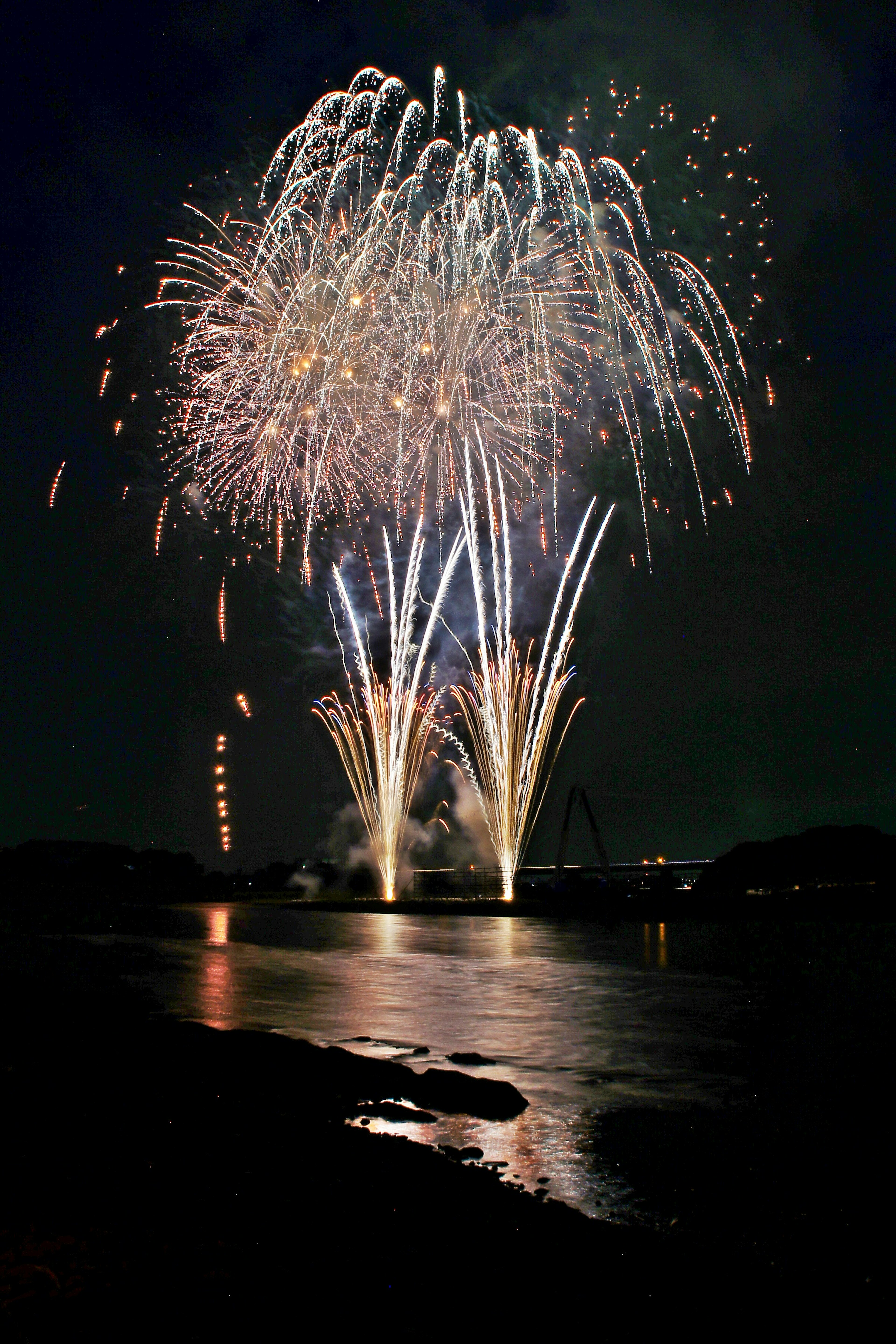 夜空に輝く花火が水面に反射している光景