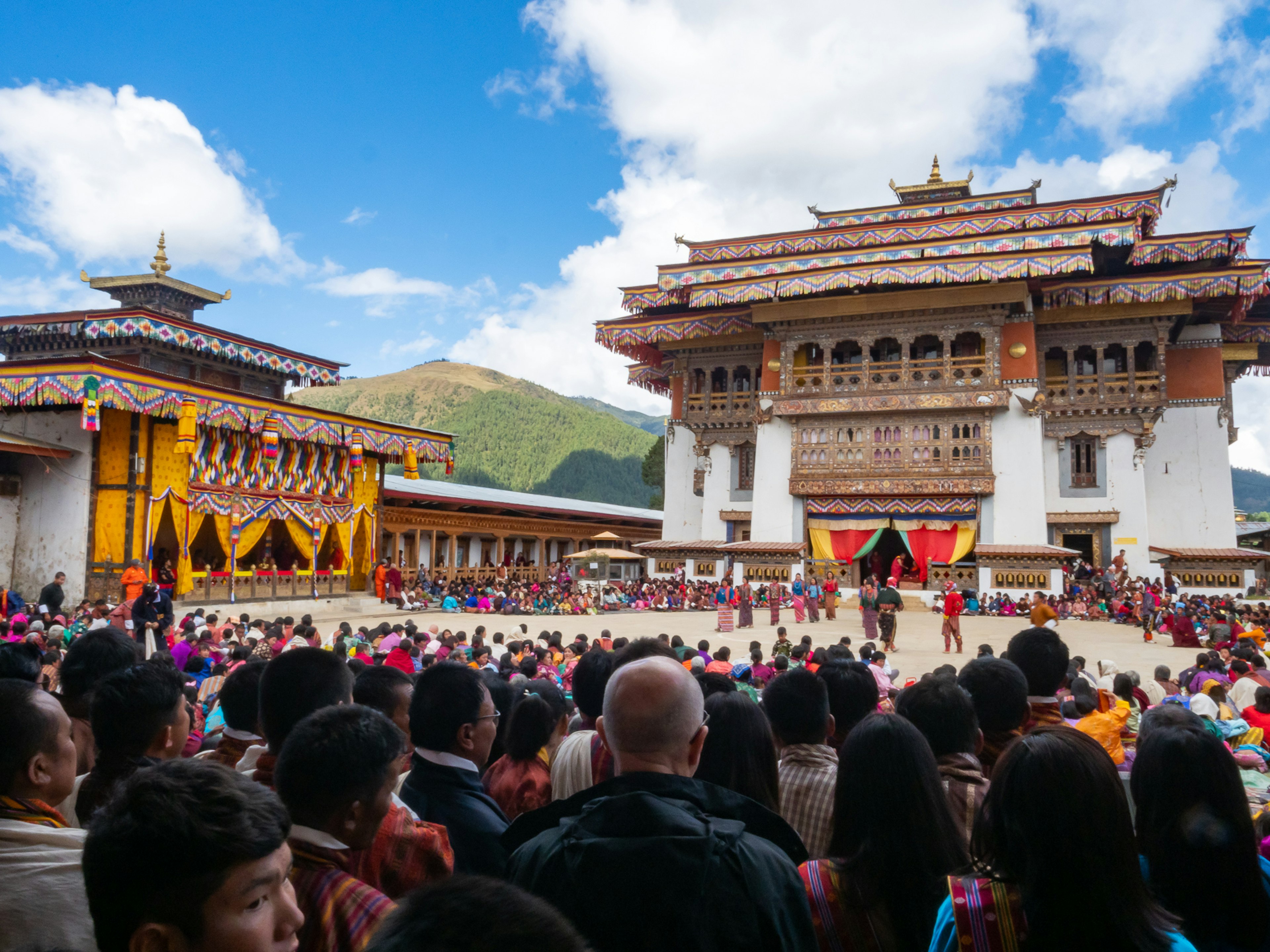 Kerumunan yang berkumpul di festival tradisional Bhutan dengan arsitektur kuil yang indah