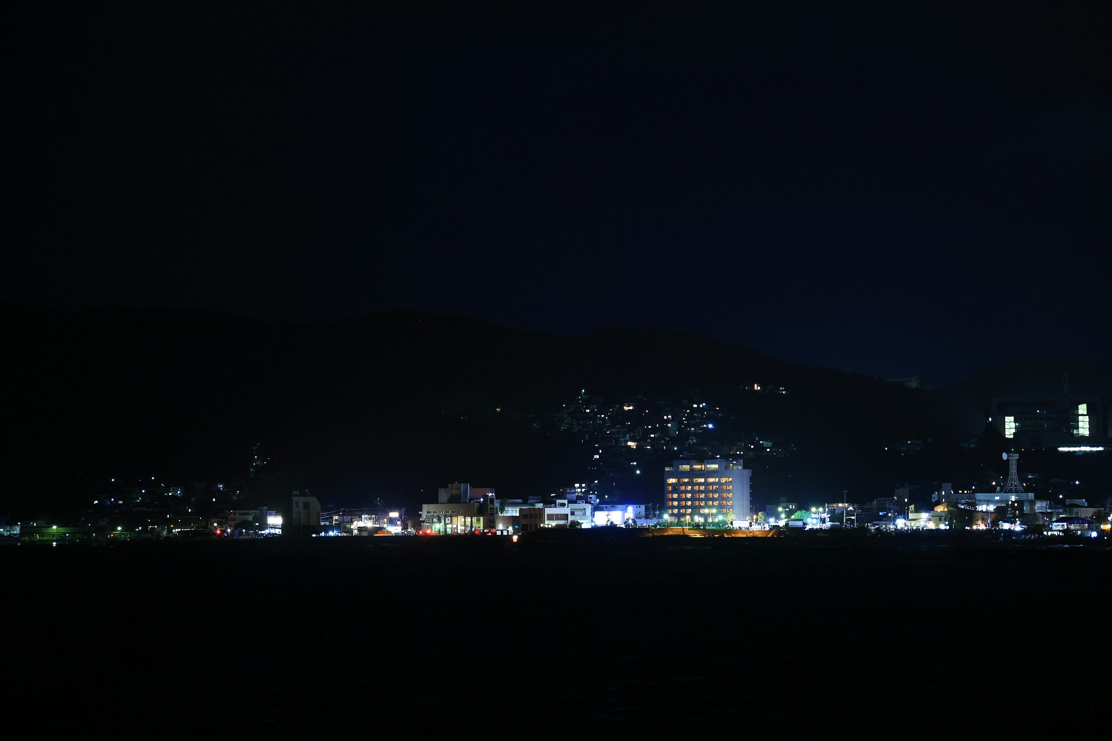 Nächtliche Aussicht auf eine beleuchtete Stadtlandschaft mit Gebäuden und Hügeln