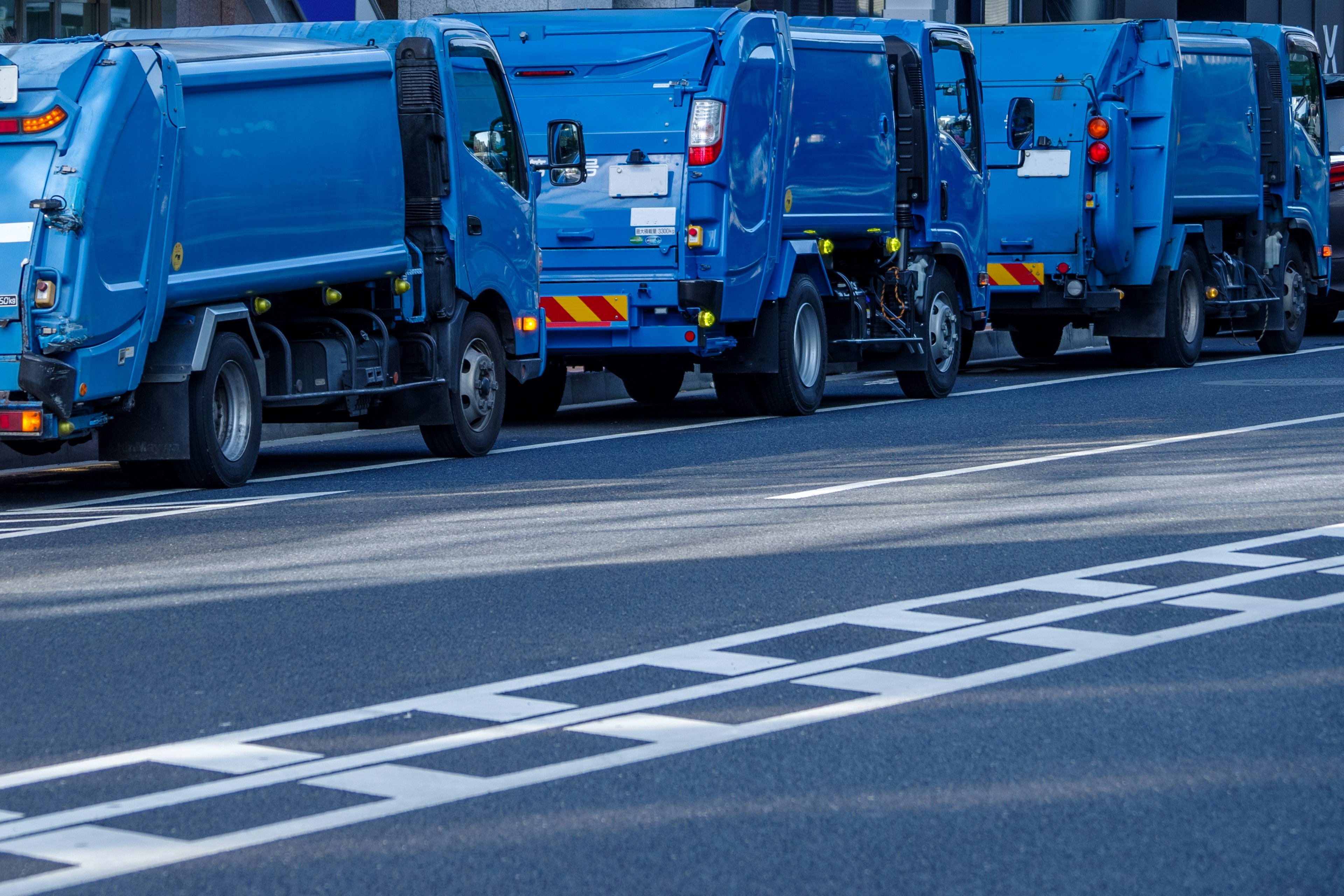 Fila di camion della spazzatura blu parcheggiati sulla strada