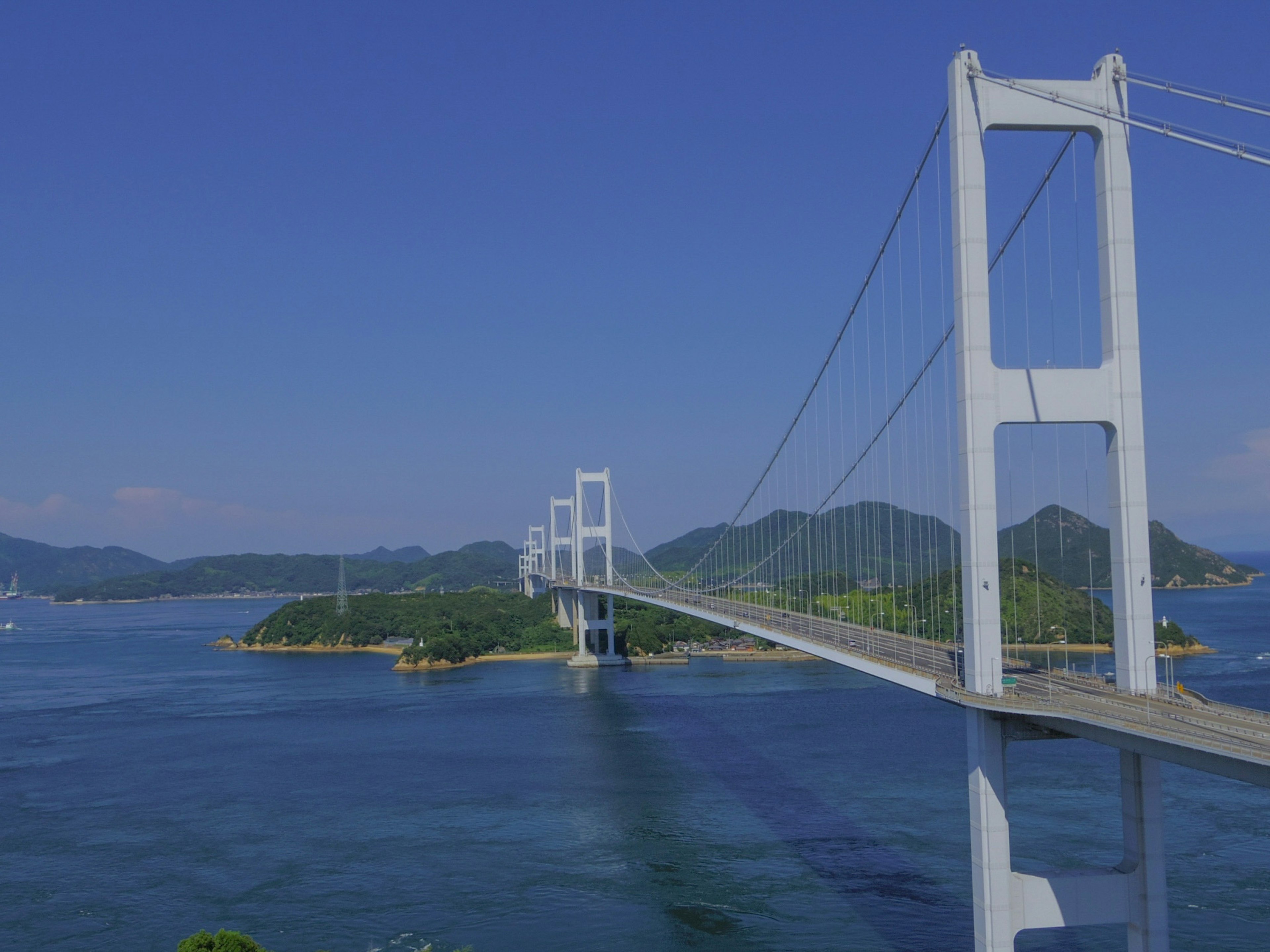 Eine Brücke, die über blaues Wasser mit grünen Inseln im Hintergrund führt