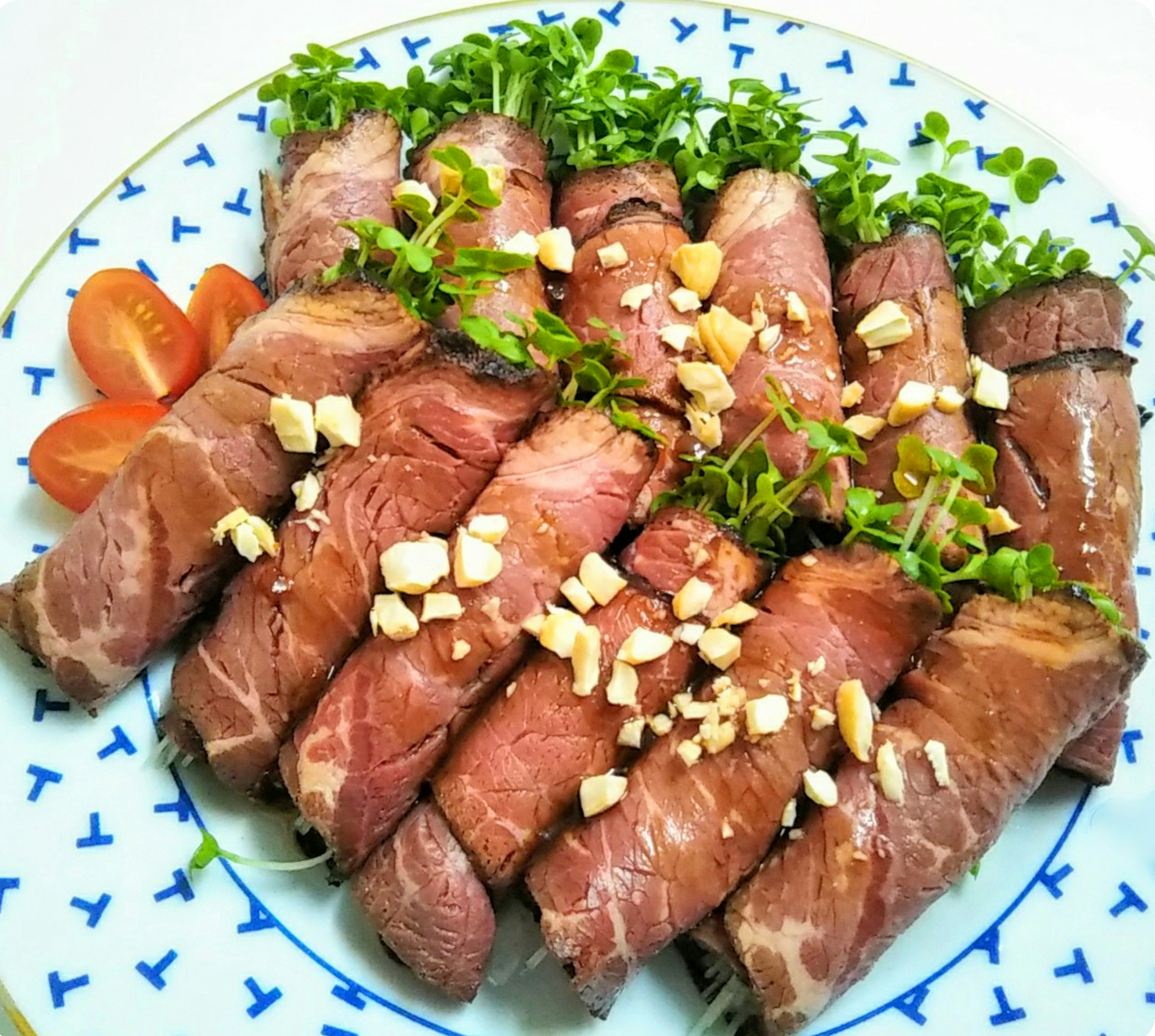 Rollos de carne de res en rodajas decorados con hierbas y cacahuetes picados