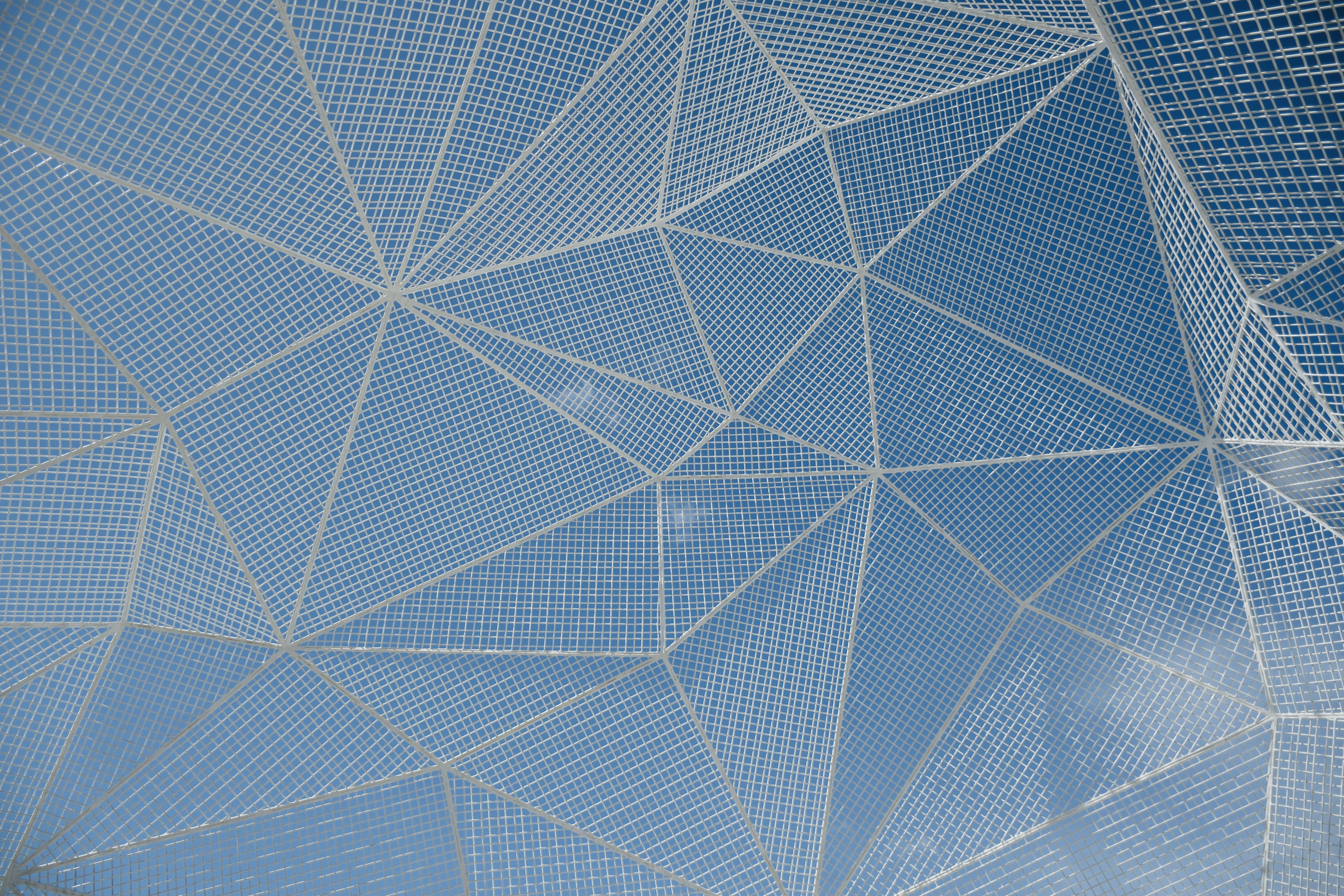 Geometric mesh structure against a blue sky