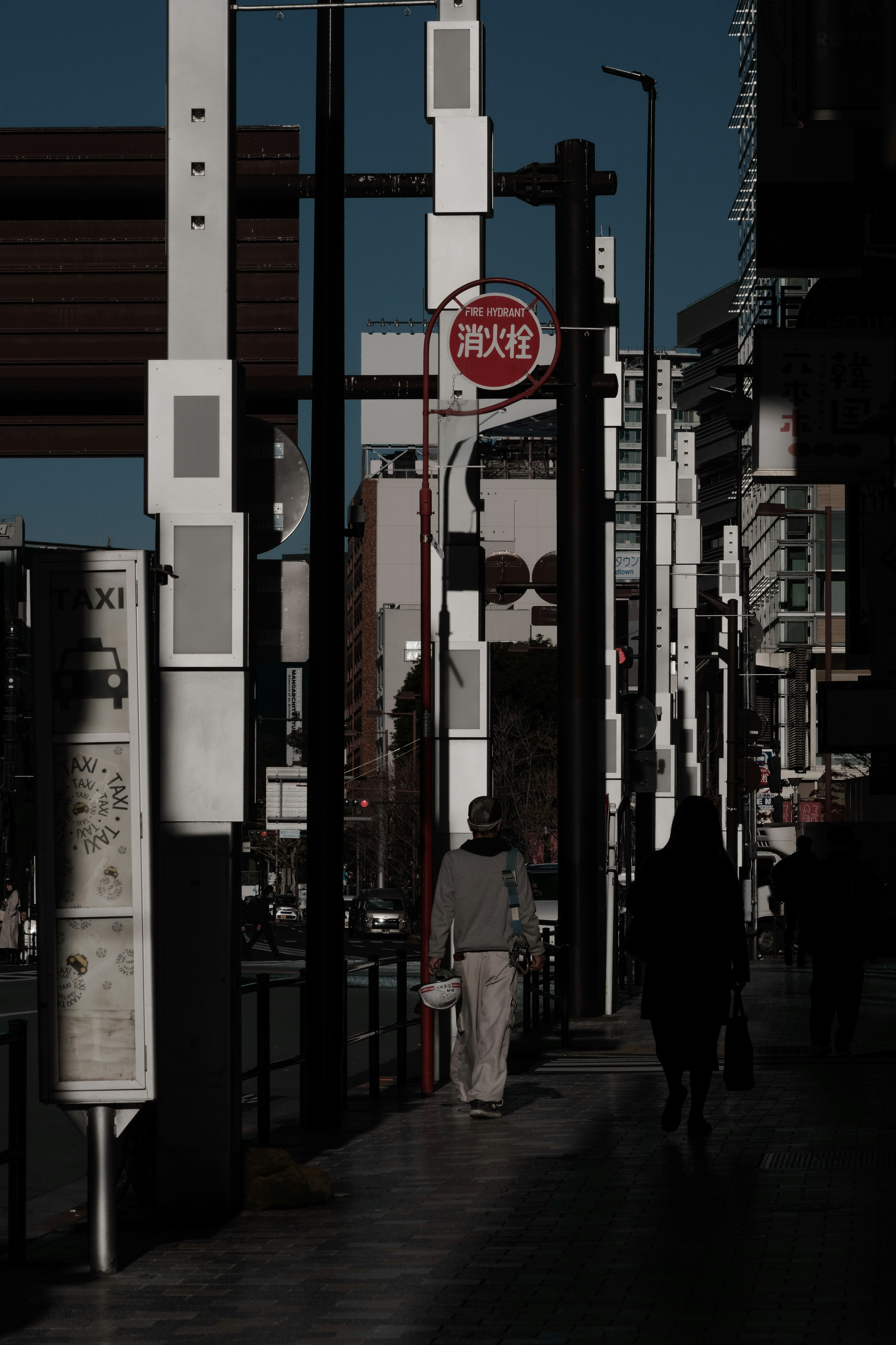 Urban street scene with pedestrians and traffic signs in shadow