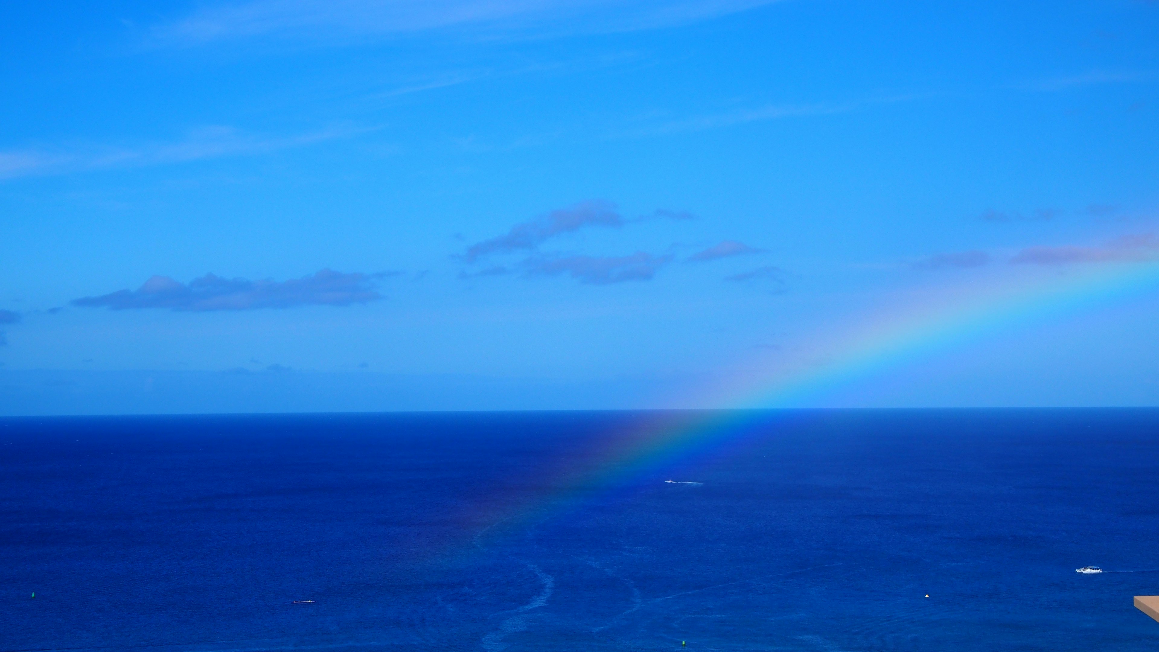 A beautiful scene of a rainbow in the blue sky and ocean