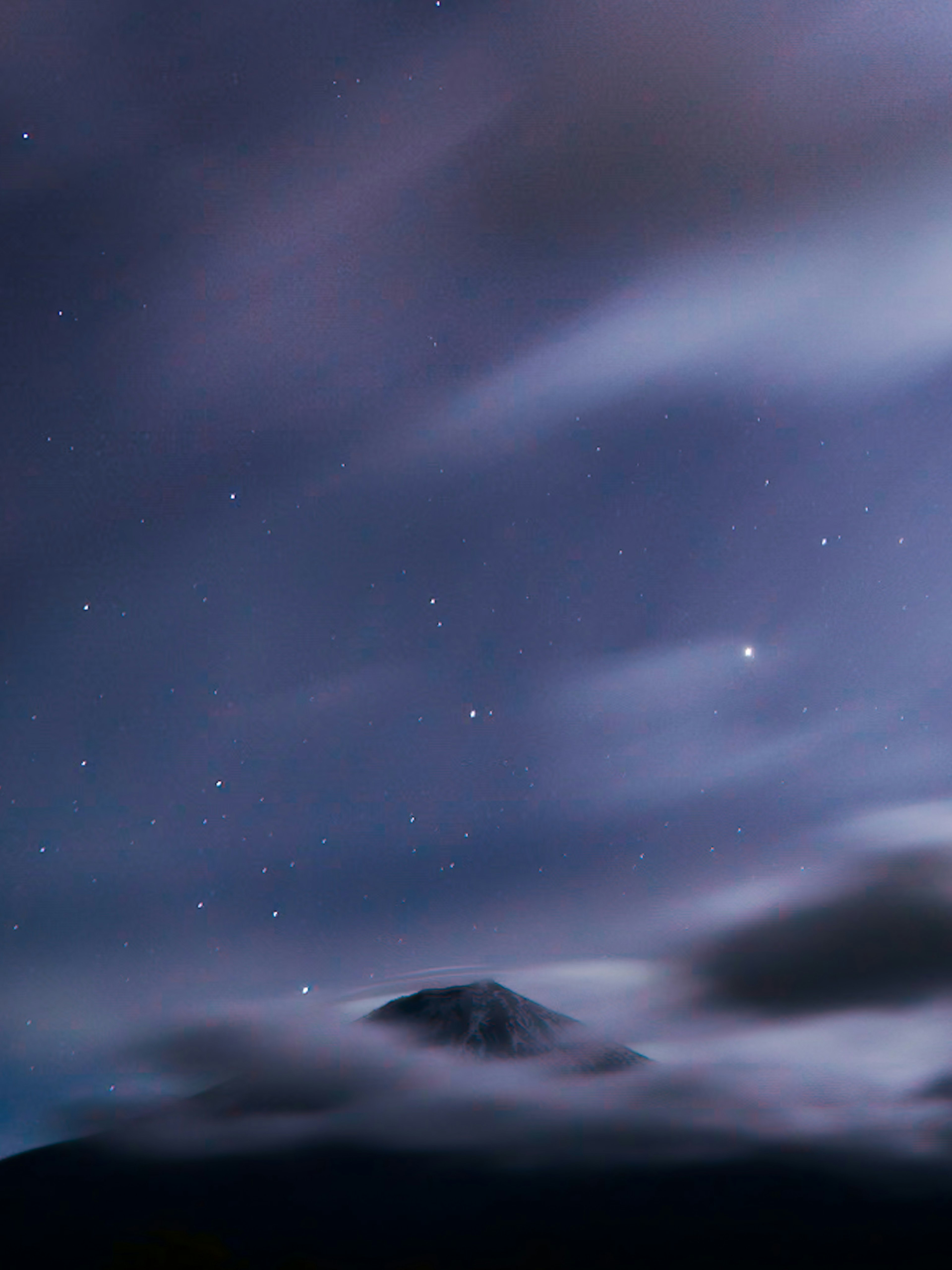 Pemandangan malam yang indah dengan gunung yang tertutup awan dan langit berbintang