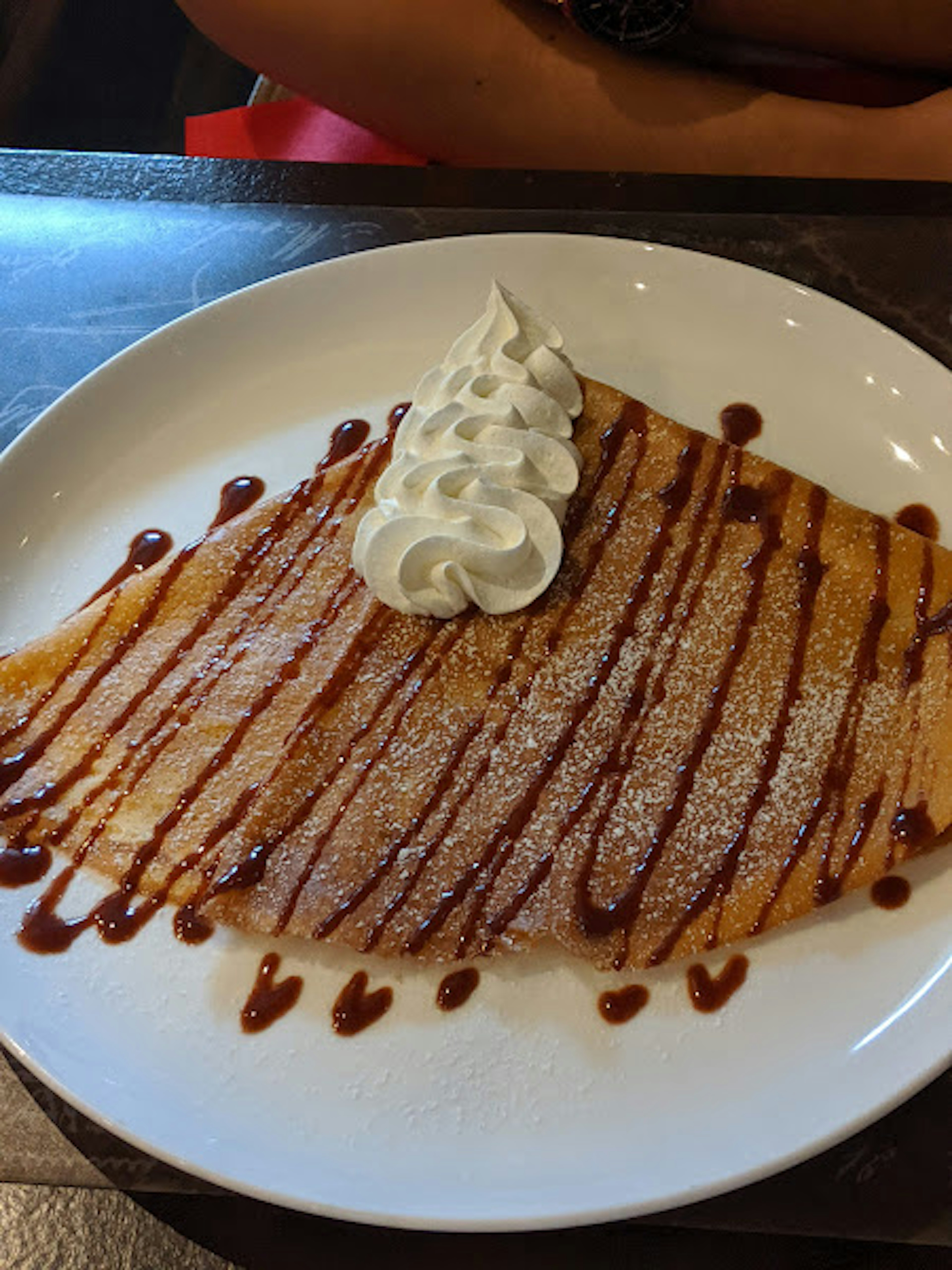 Crepe cubierta con crema y salsa de chocolate