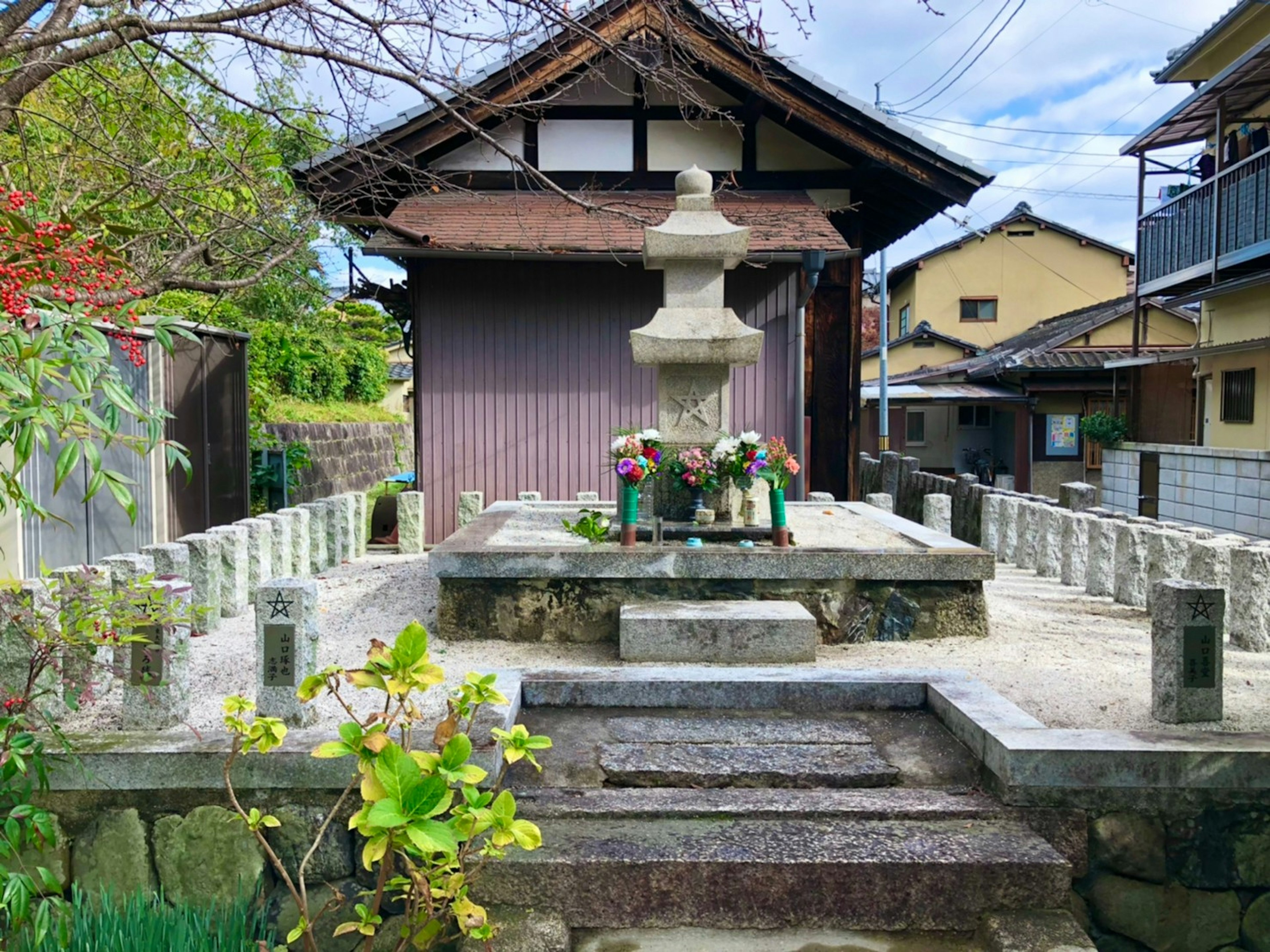 伝統的な日本建築の背景にある石の灯篭と花が飾られた祭壇