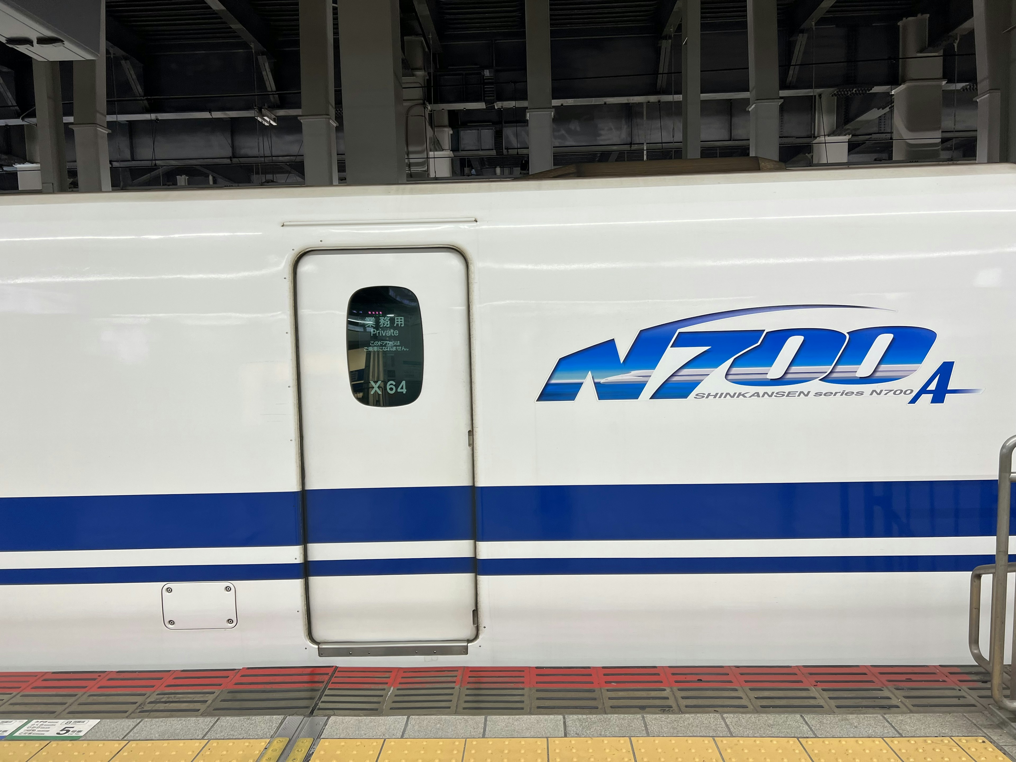 Vista laterale del Shinkansen N700A con logo blu e finestra