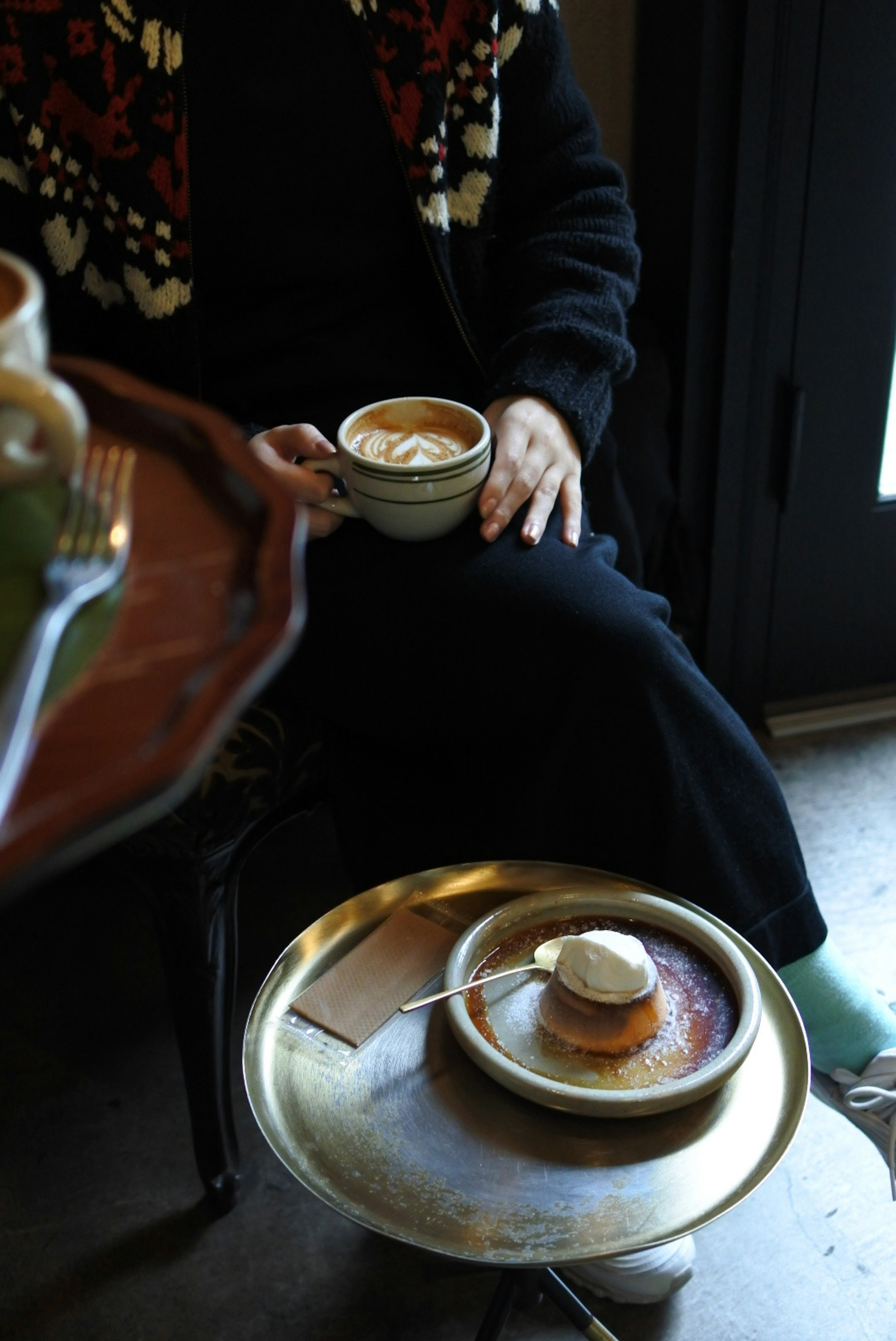 Person holding a coffee cup with dessert on a table