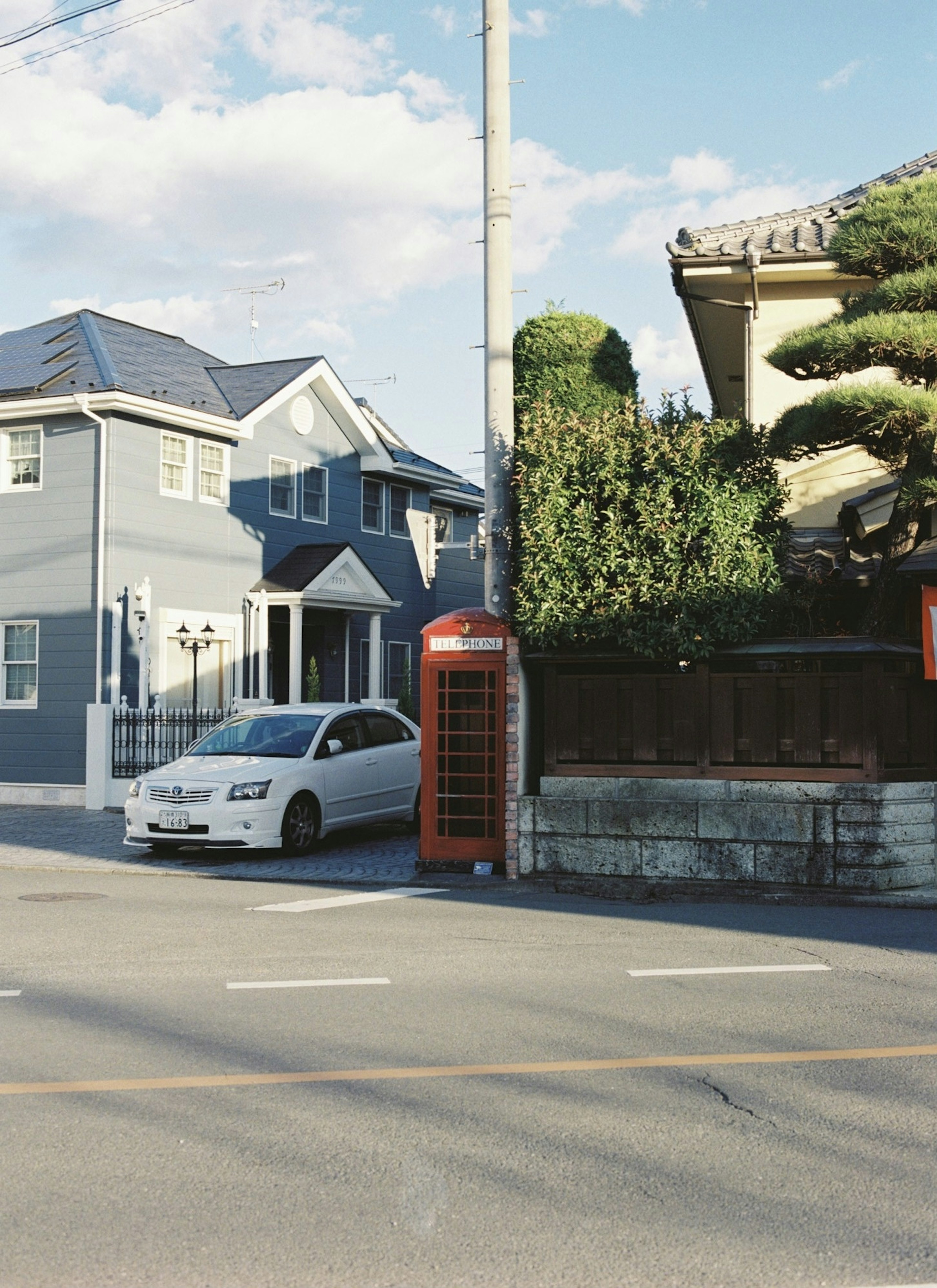 Coin de rue avec une maison bleue et une cabine téléphonique rouge