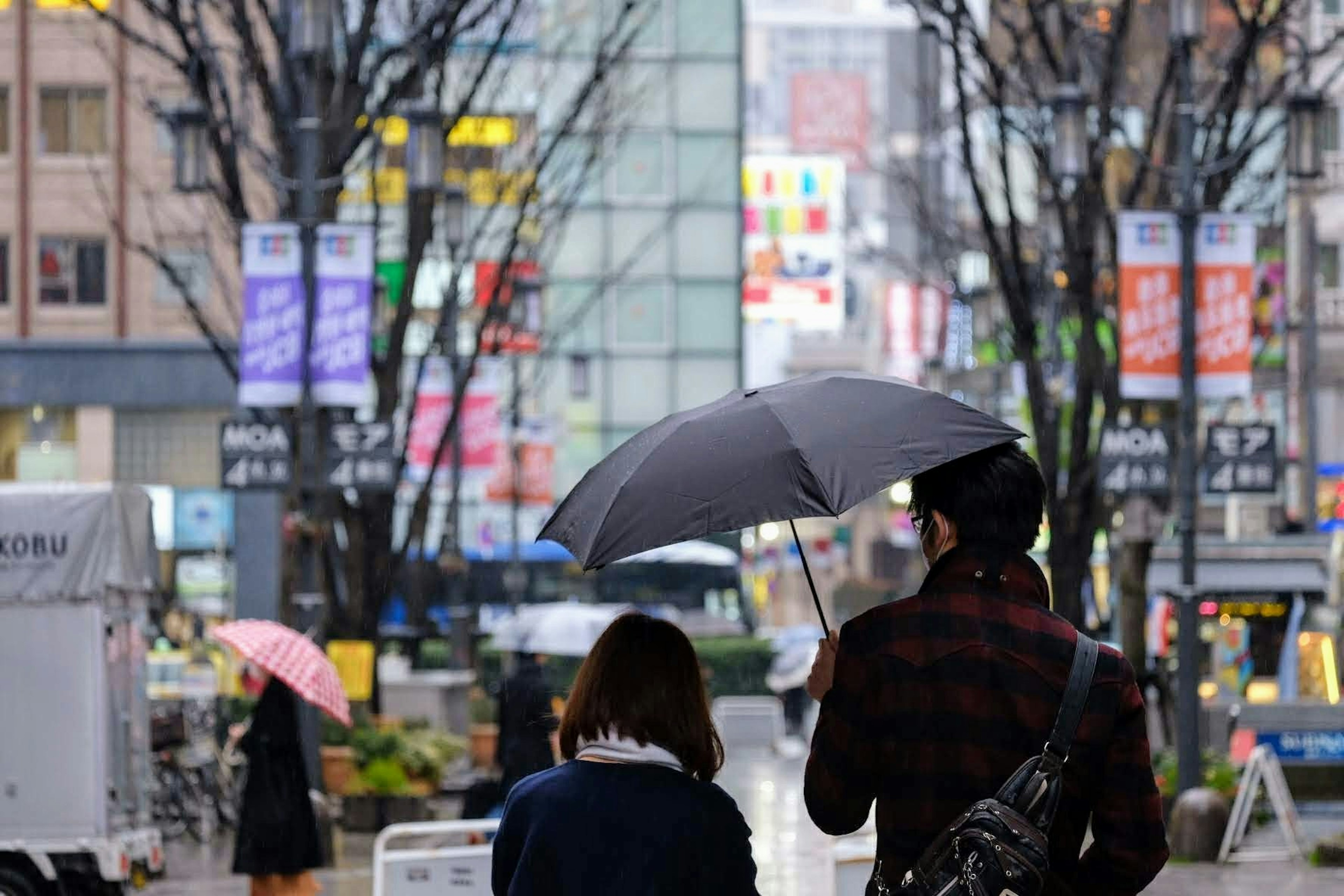 一对情侣在雨中走在城市街道上，打着伞