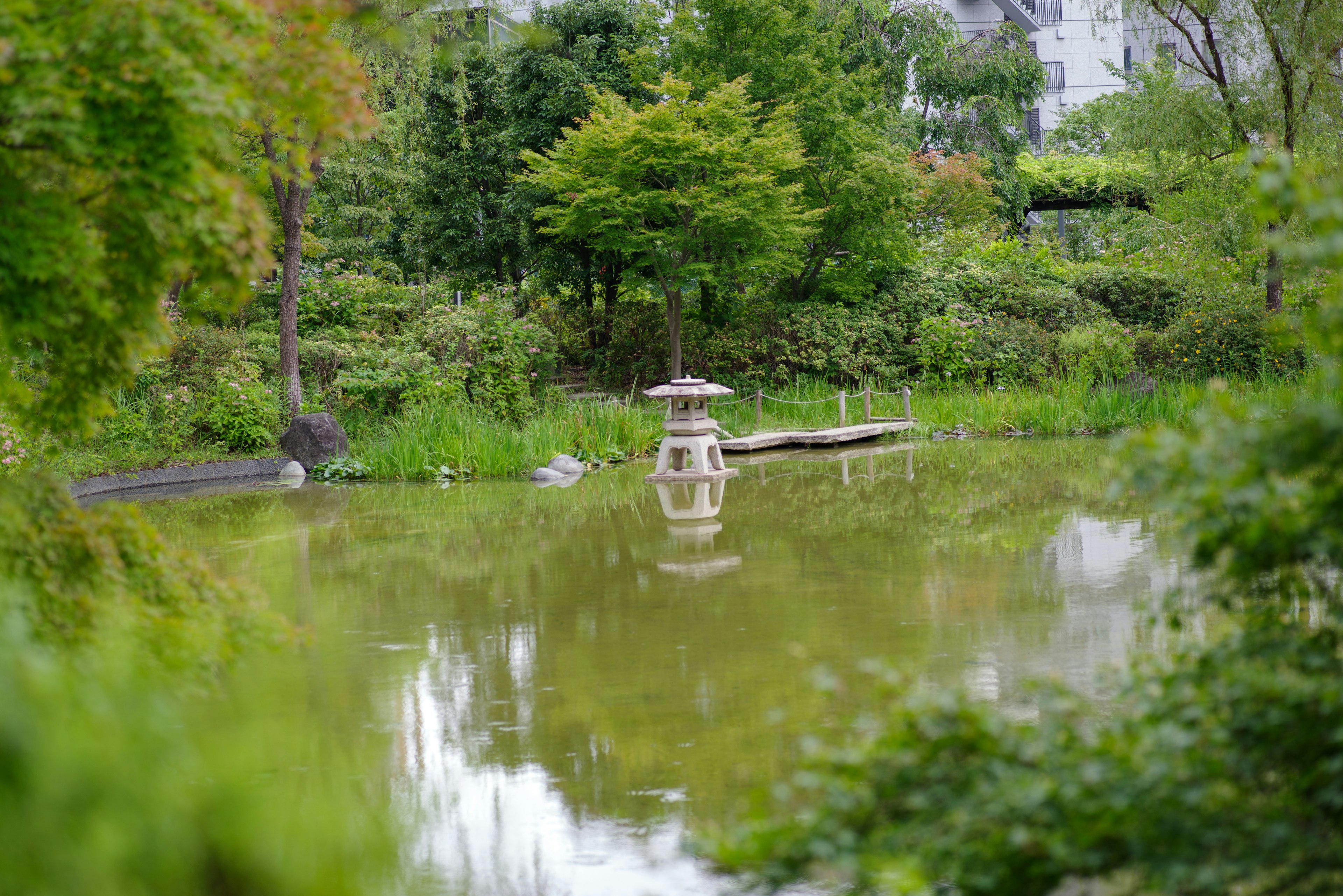 静かな池と緑豊かな風景に立つ灯籠