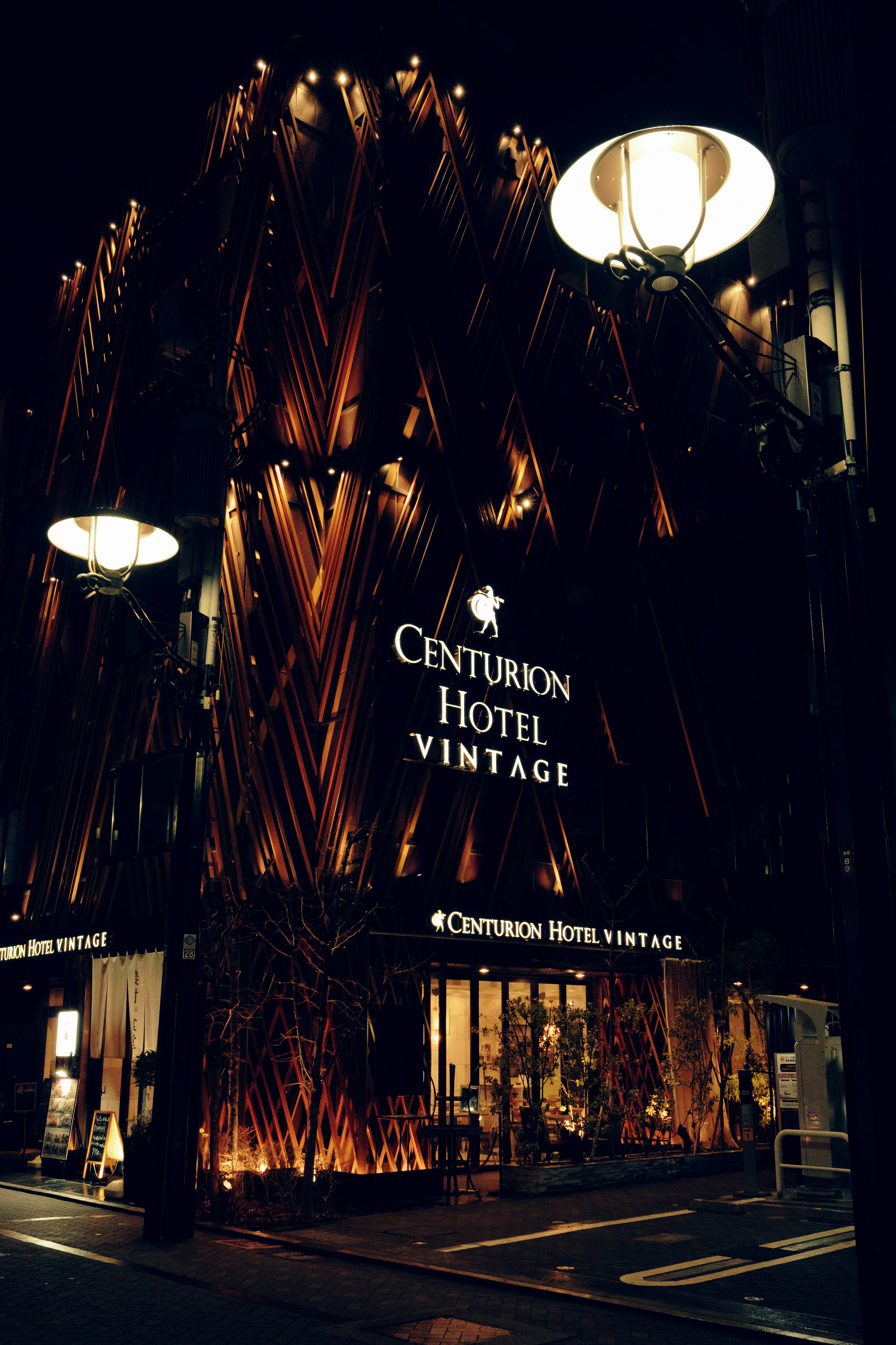 Exterior of Centurion Hotel Vintage illuminated at night with wooden decor and modern design