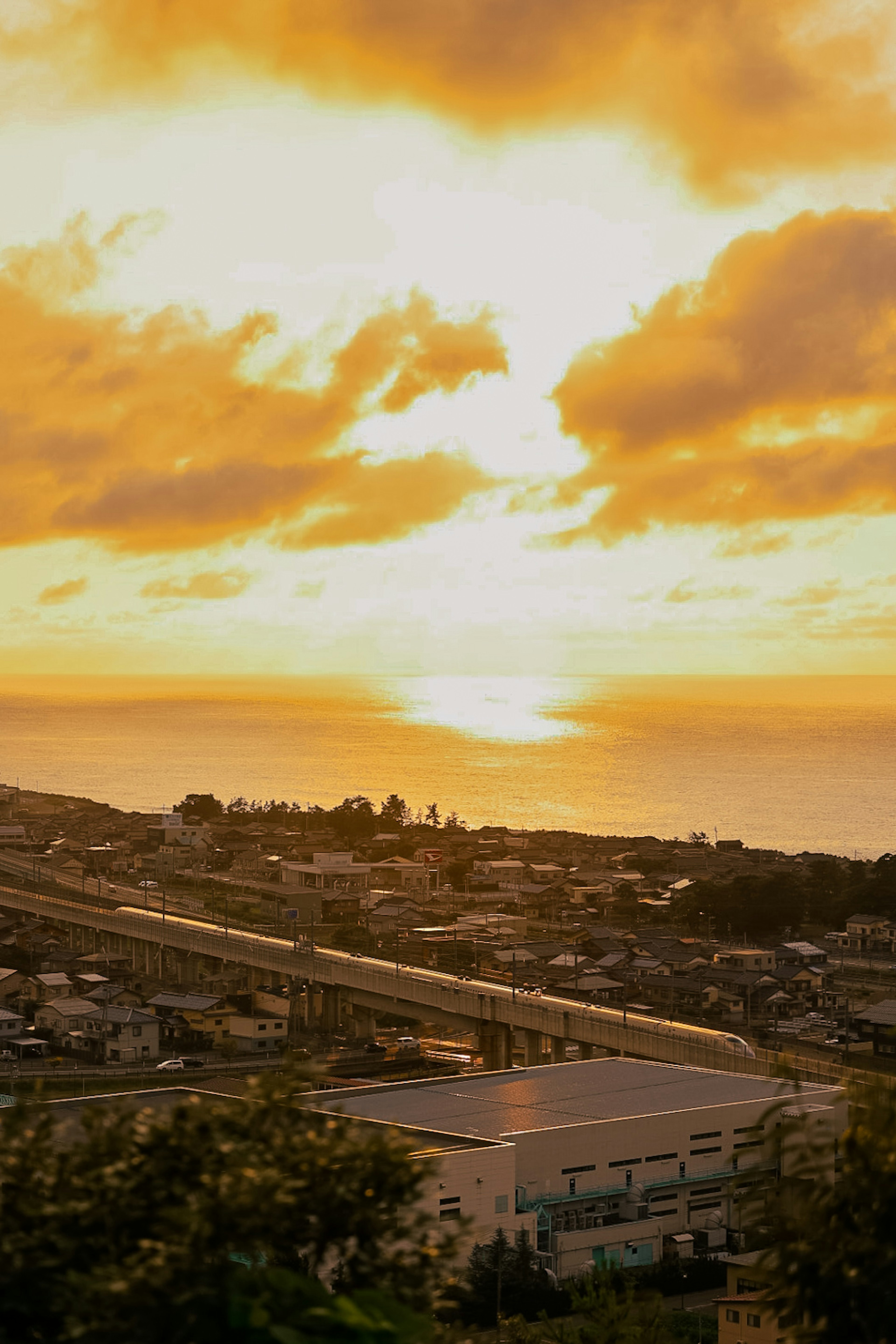 Scenic view of a sunset over the ocean with vibrant orange clouds and a coastal town