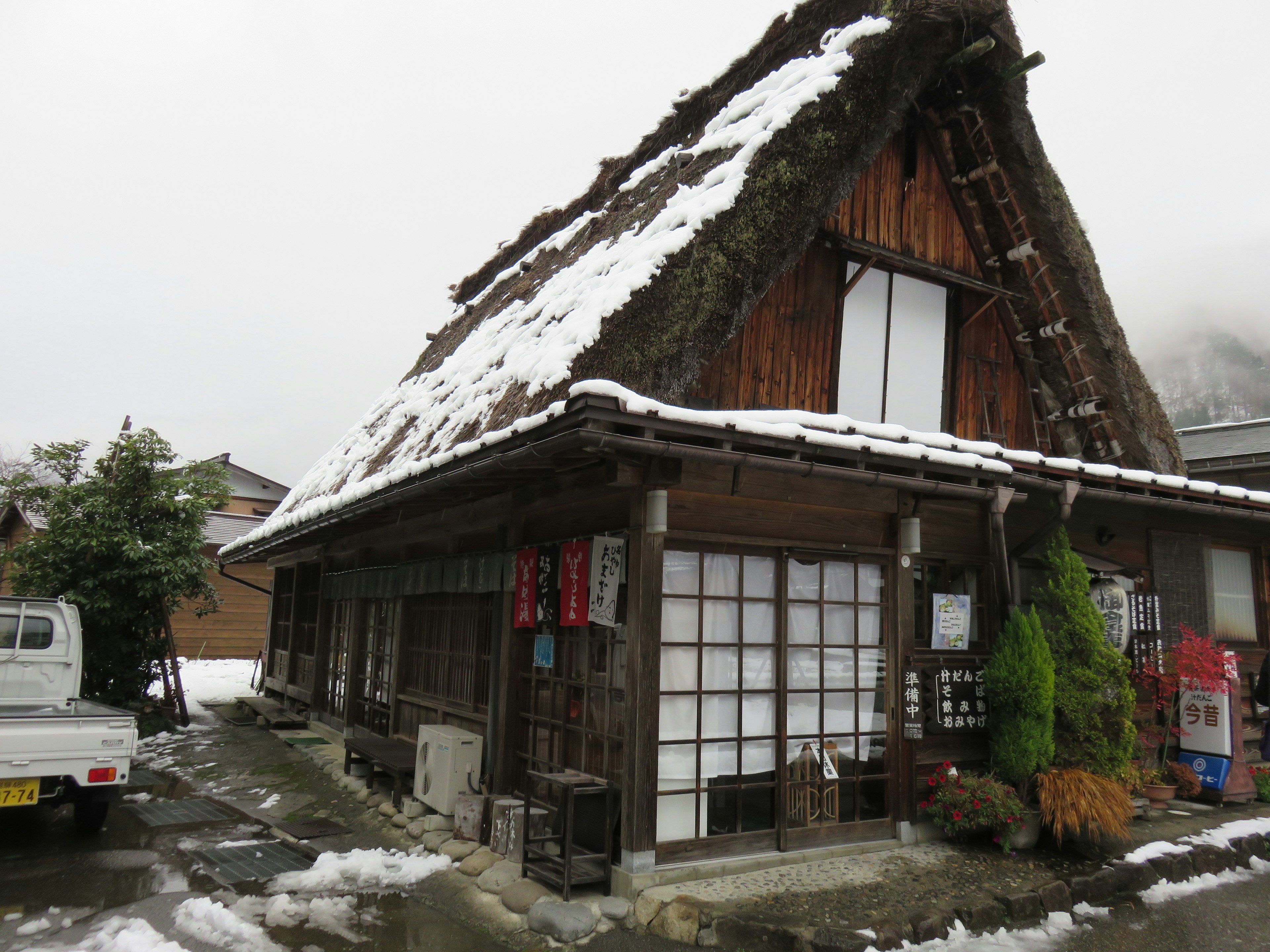 Traditional gassho-zukuri house covered in snow with surrounding landscape