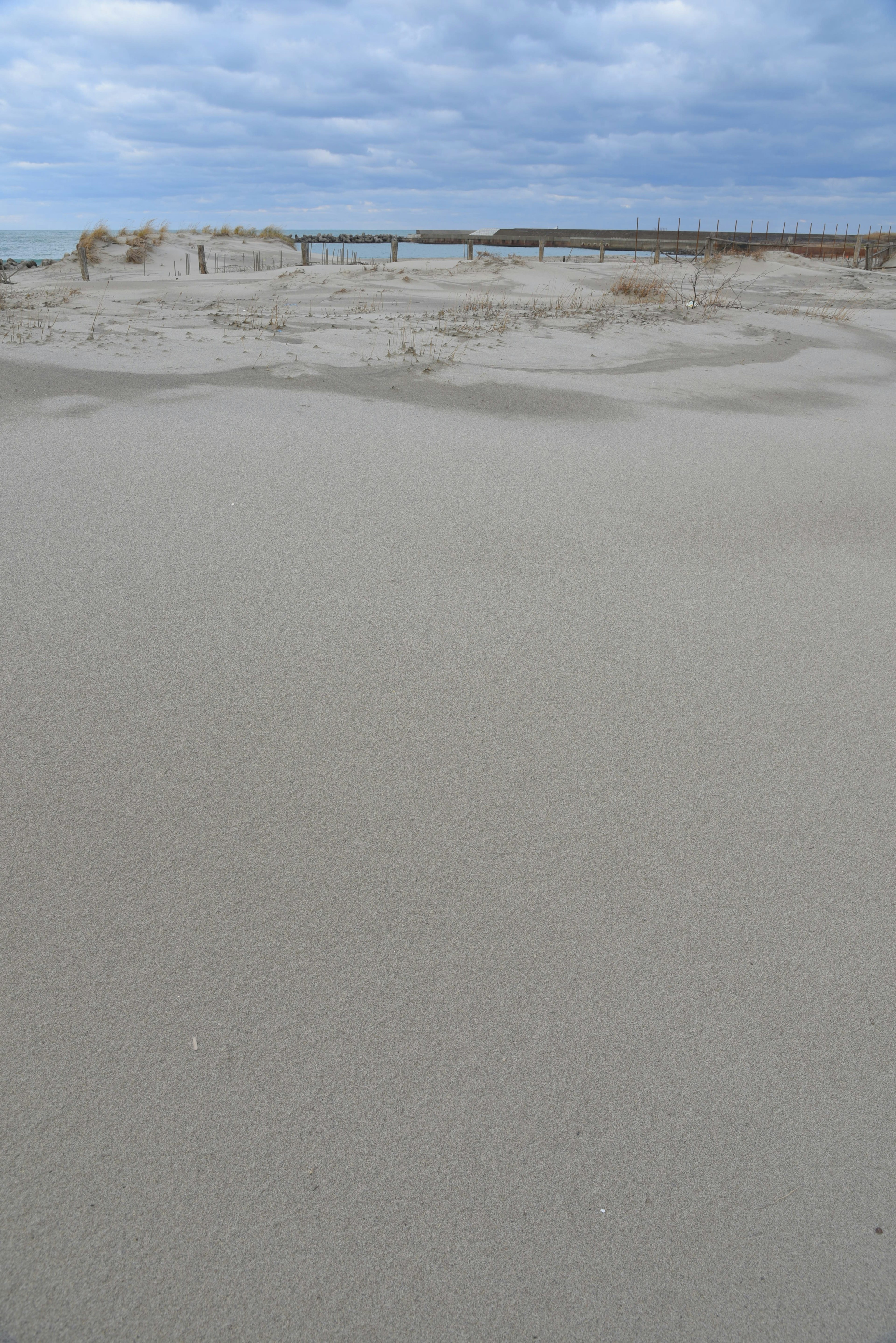 Pemandangan pantai dengan permukaan berpasir dan langit mendung