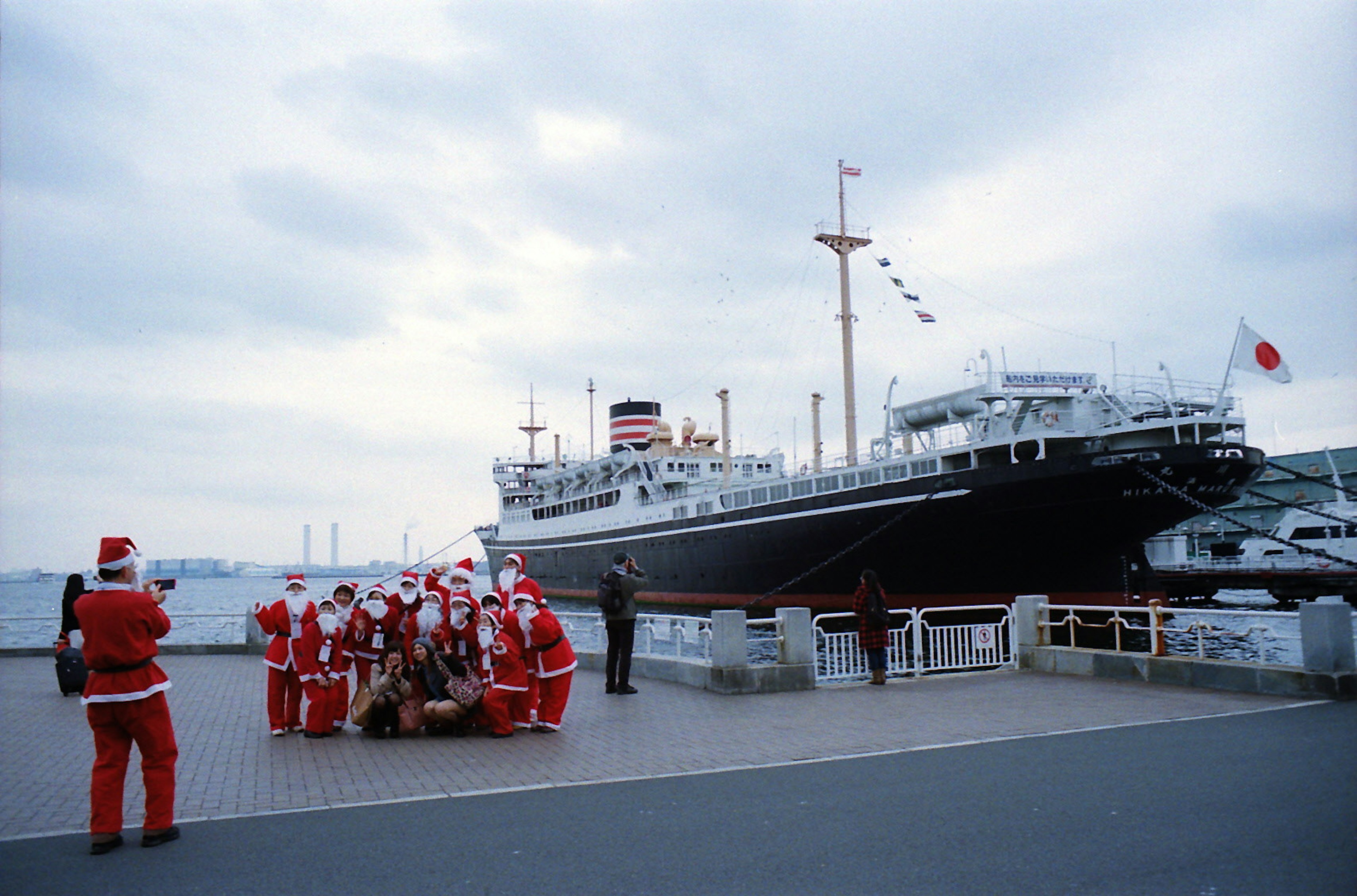 Groupe de personnes en costumes de Père Noël rassemblées devant un bateau