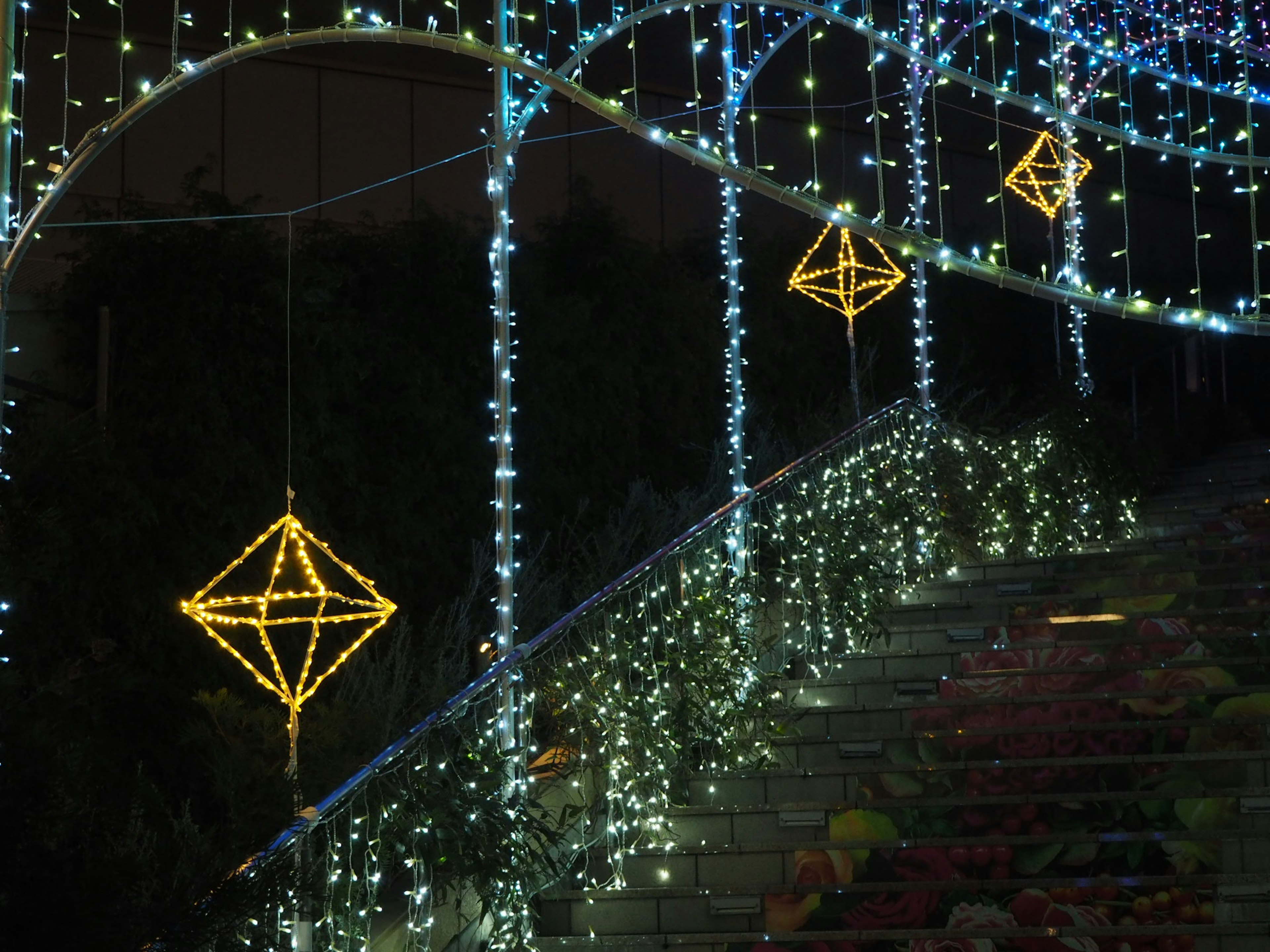 Dekorative goldene Würfelornamente hängen unter Nachtlichtern und blau-weißen LED-Lichtern