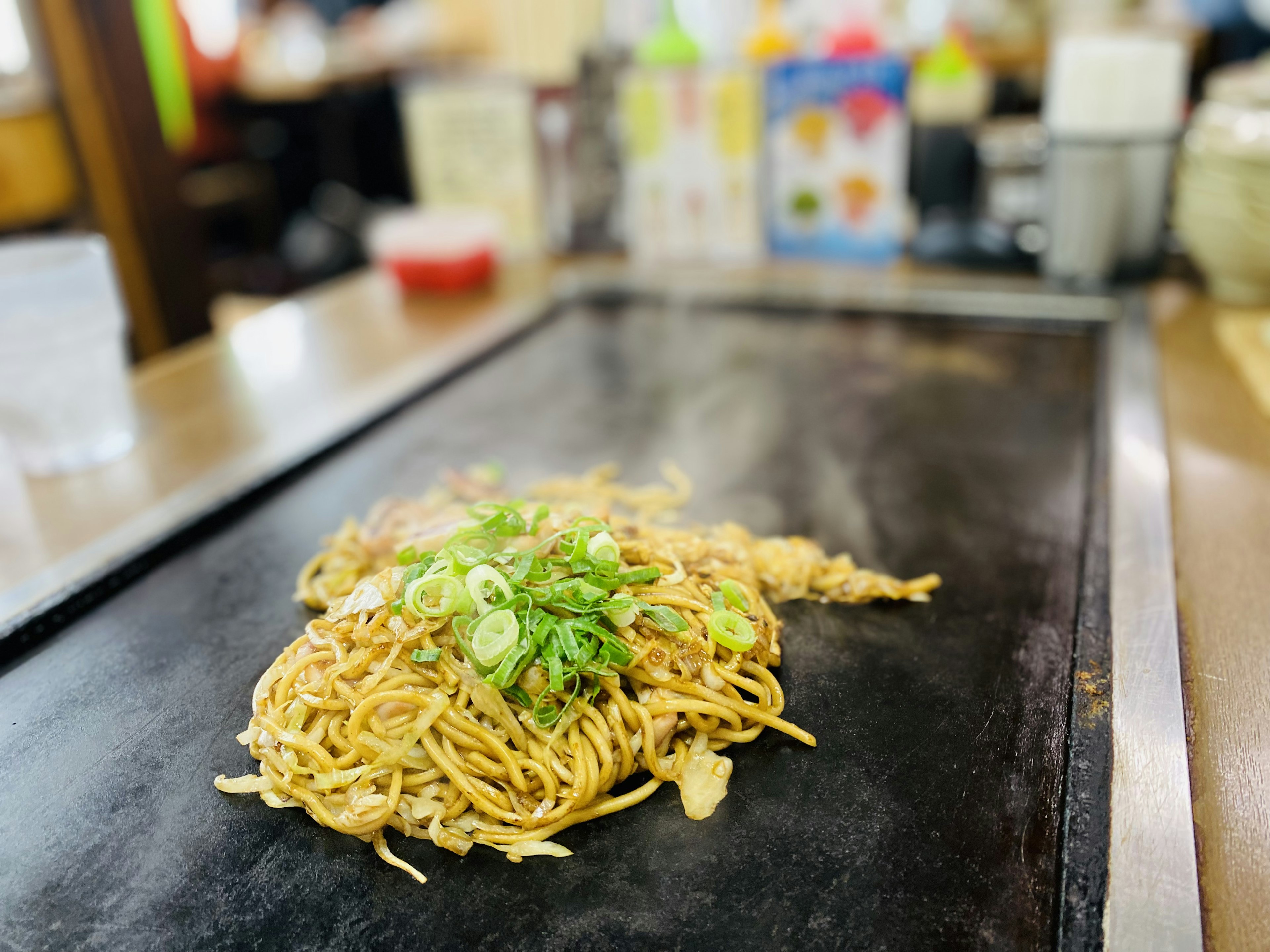 Yakisoba disajikan di atas teppan dengan daun bawang