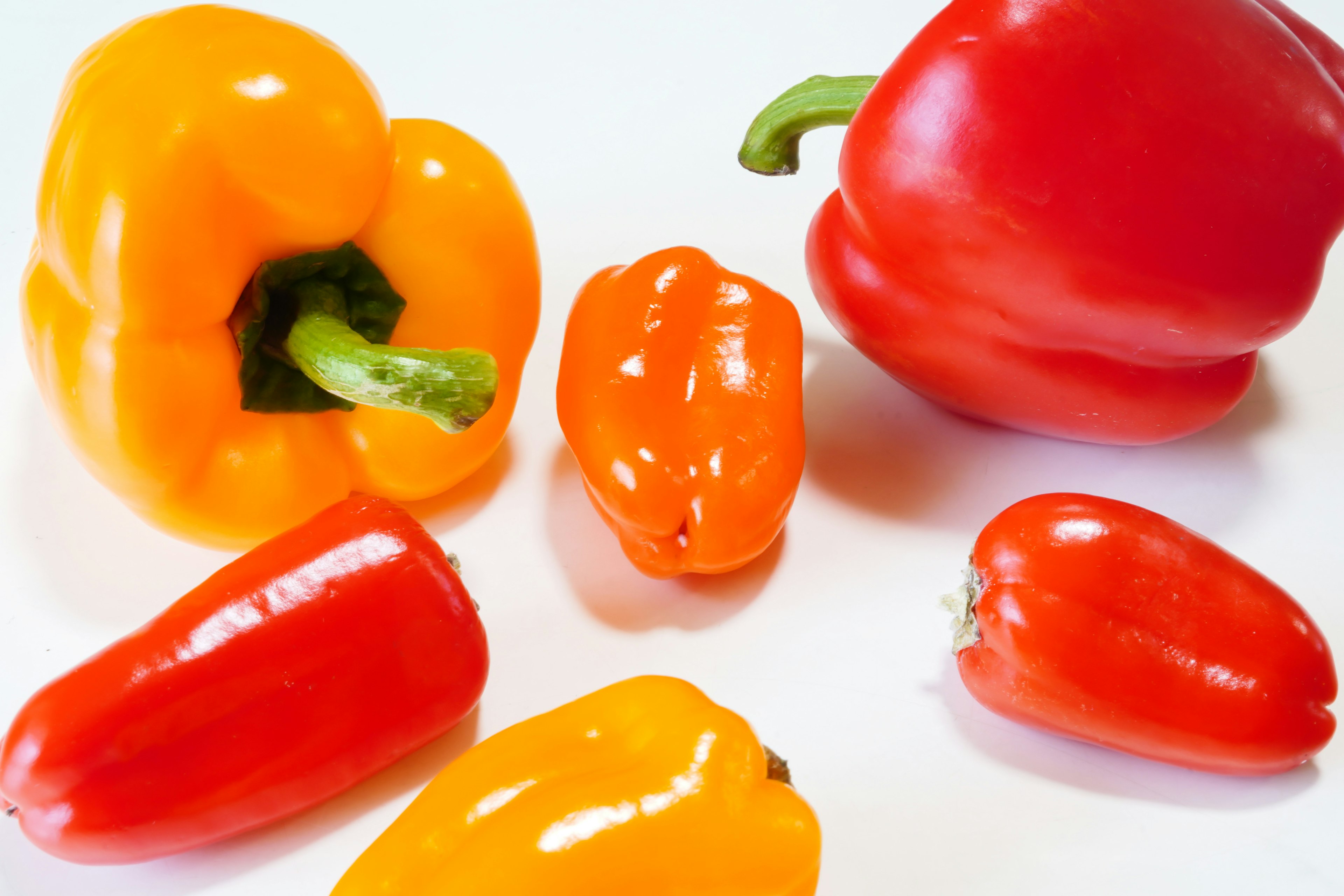 Colorful bell peppers and small chili peppers arranged on a white surface