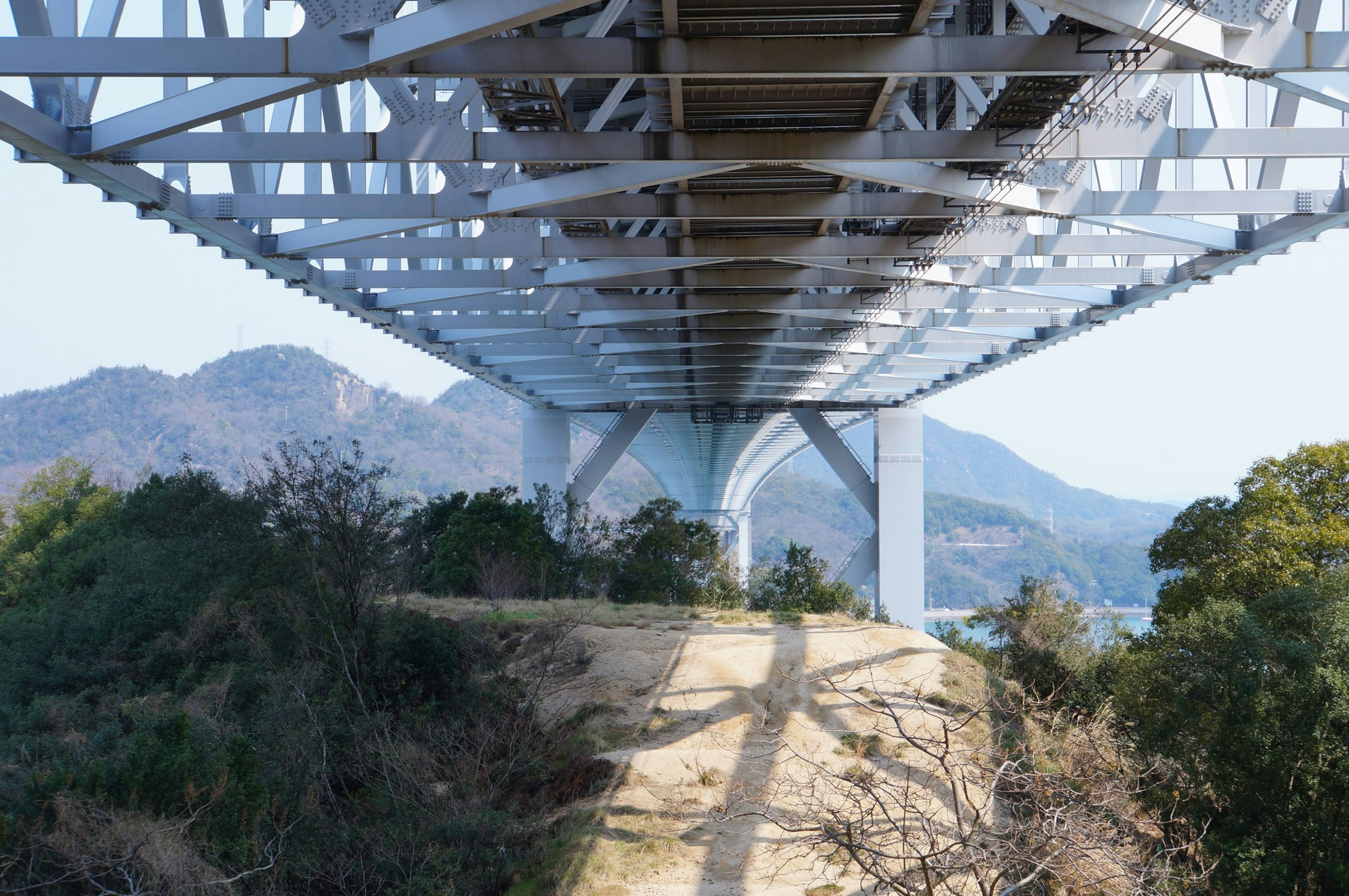 Pemandangan struktur jembatan dari bawah dengan pemandangan alam sekitar