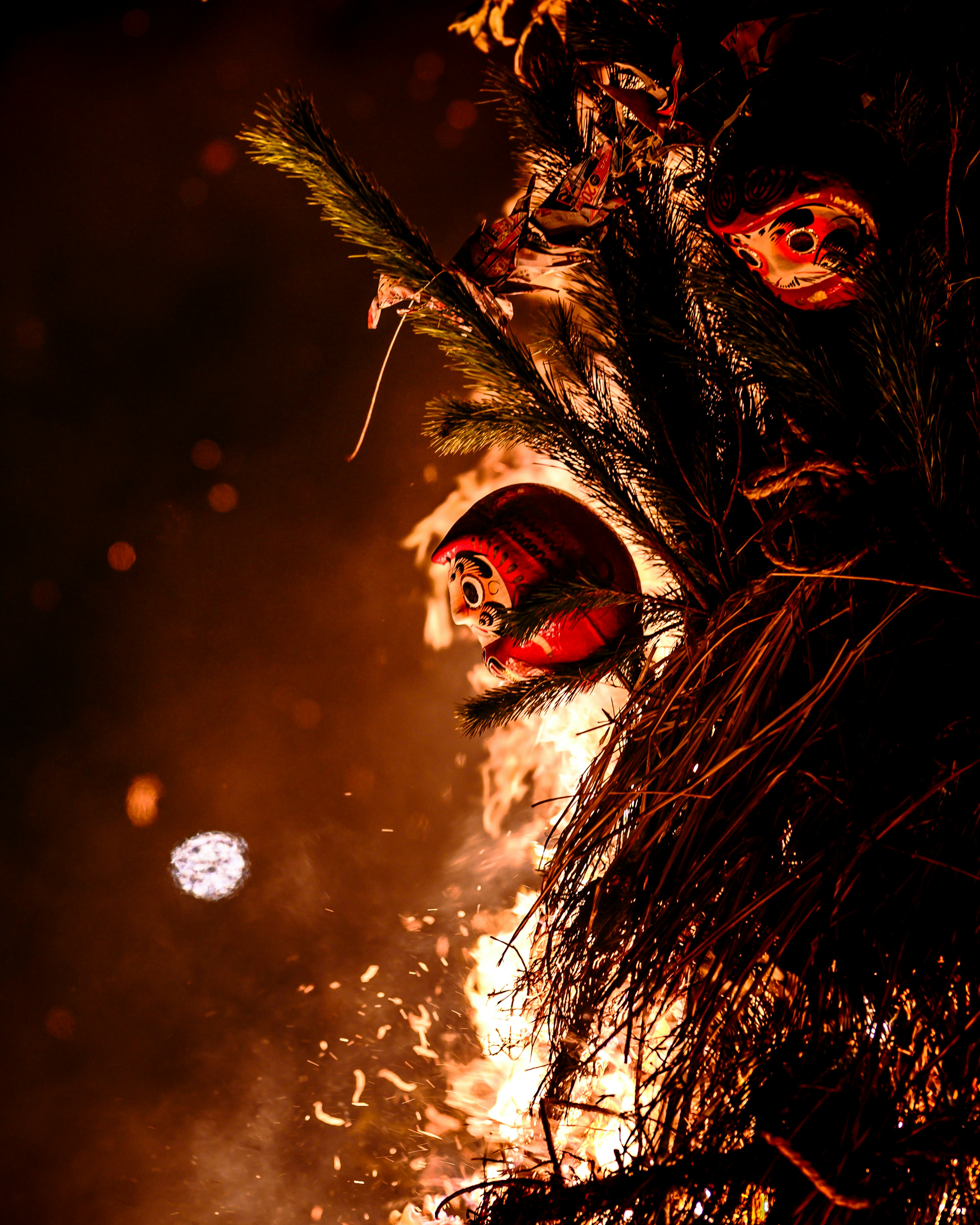 Image of Daruma dolls surrounded by flames and pine branches