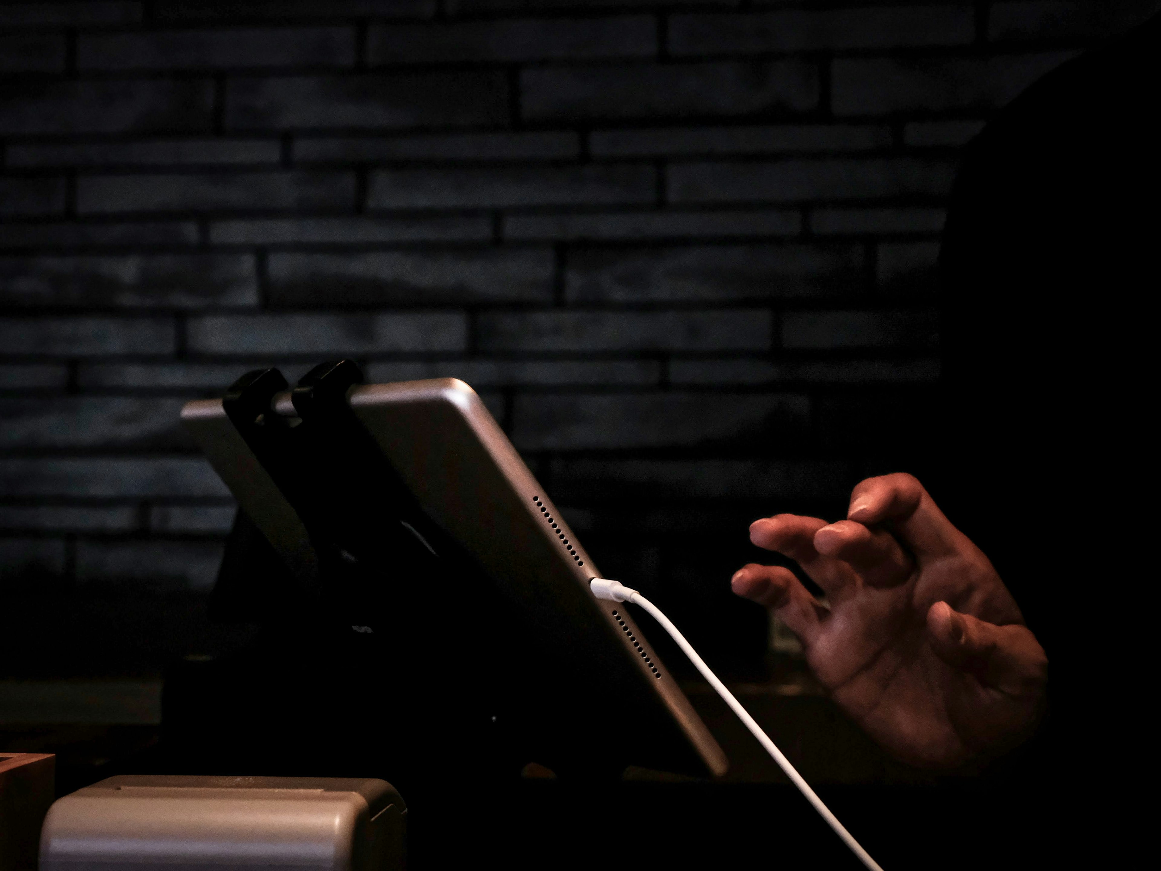 Tablet on a stand with a hand gesturing in a dimly lit setting