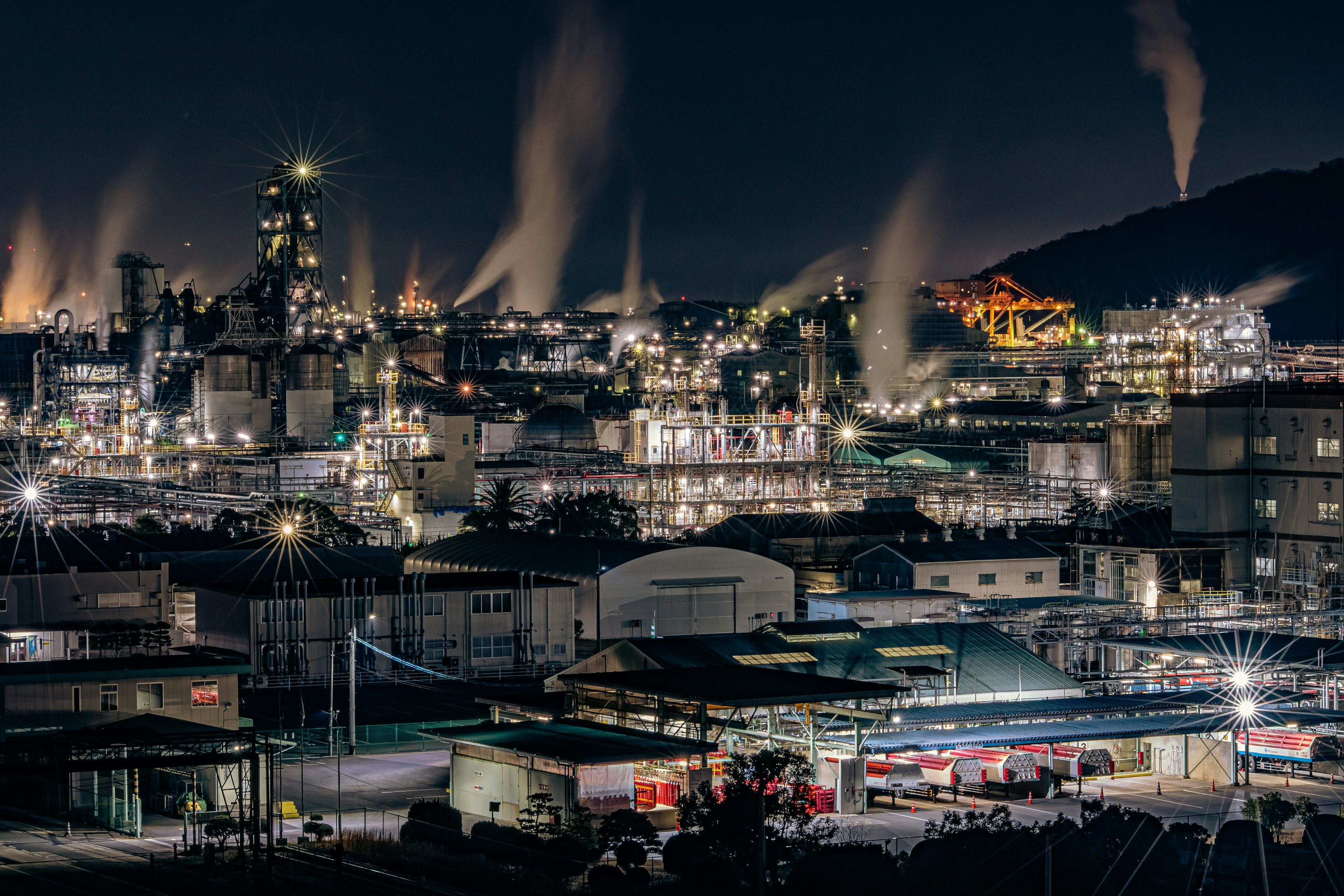 夜間工業景觀，明亮的燈光和煙囪冒出的煙霧