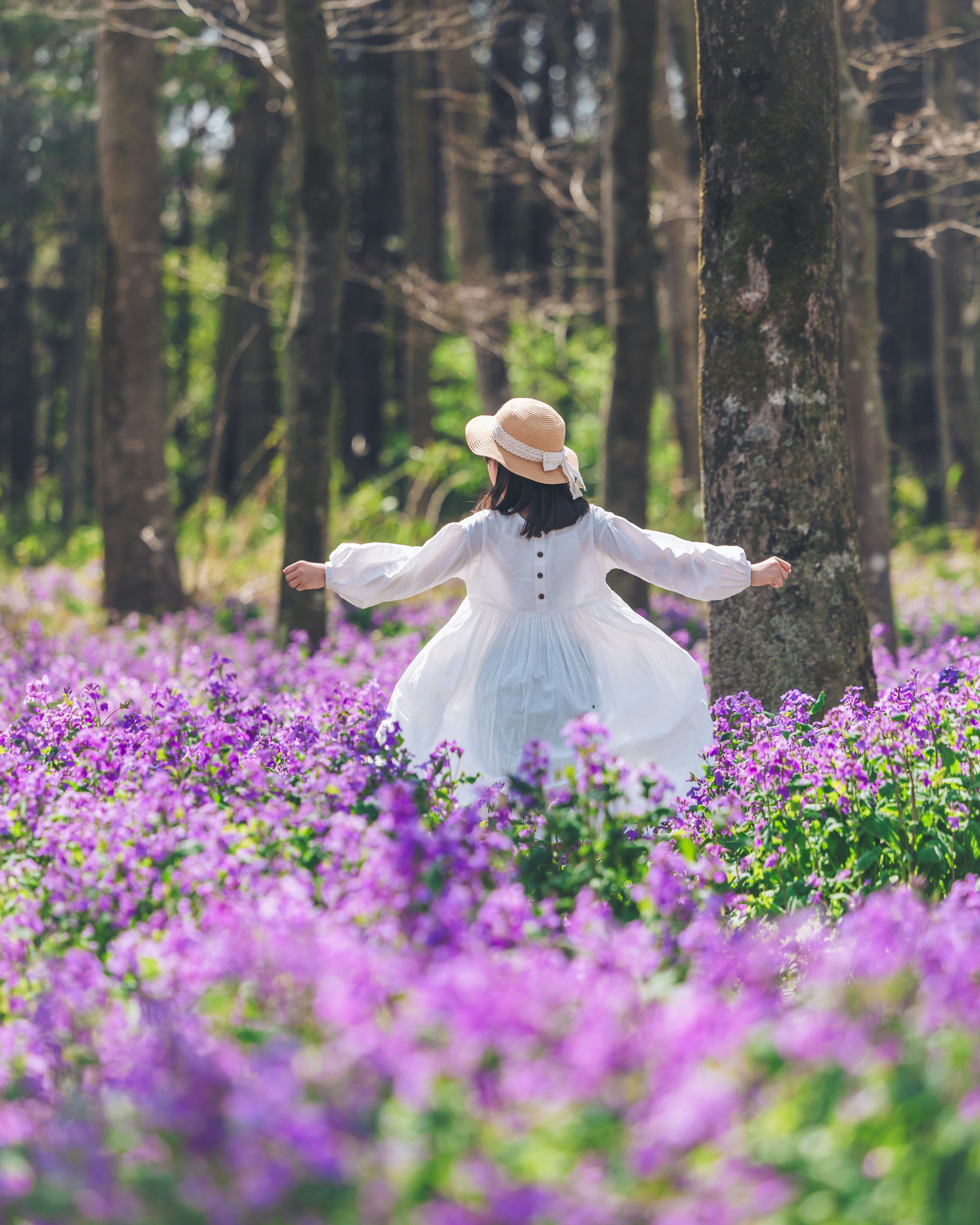 紫色の花に囲まれた白いドレスの女性が楽しそうに踊っている