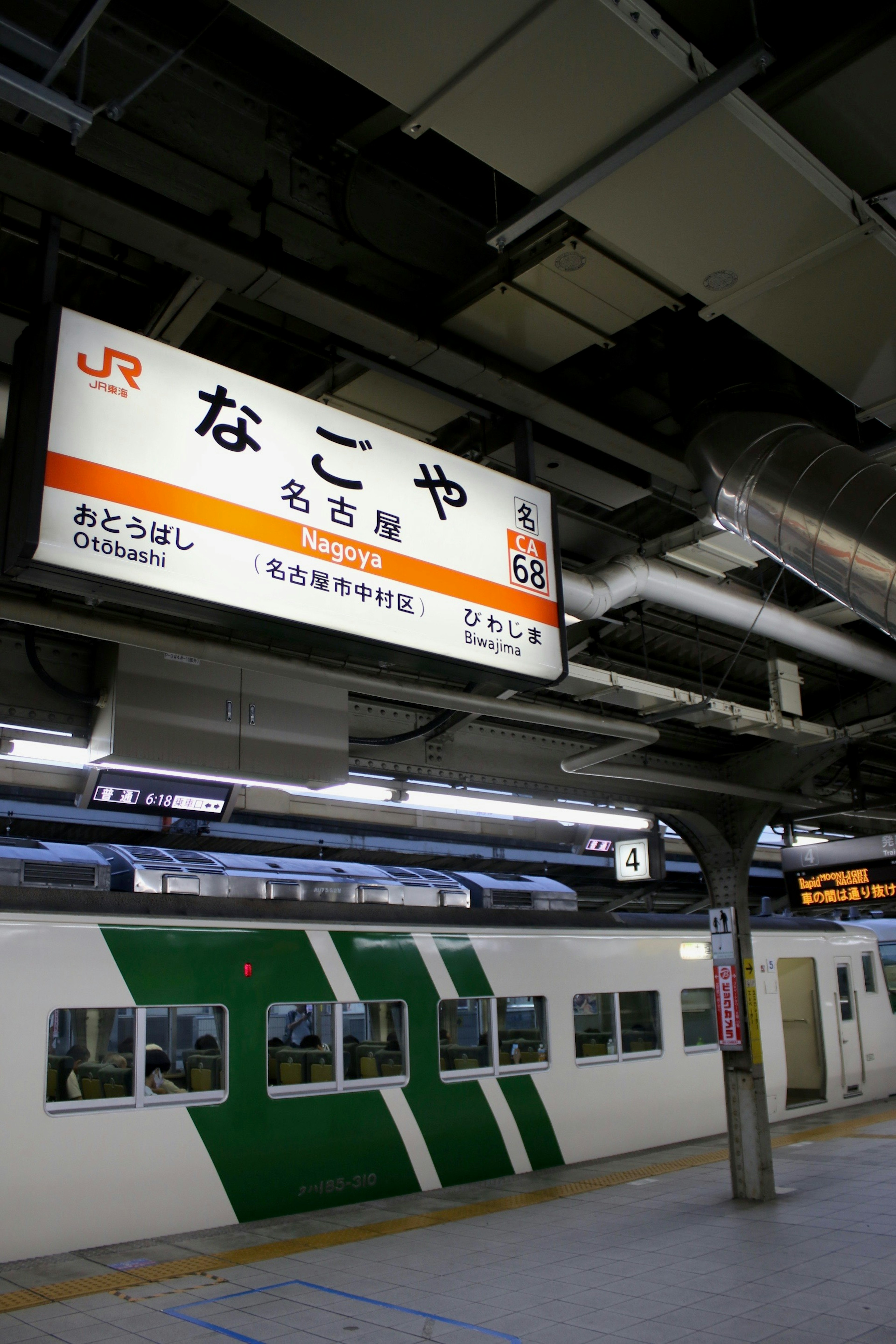 Piattaforma della stazione di Nagoya con un treno e un cartello della stazione