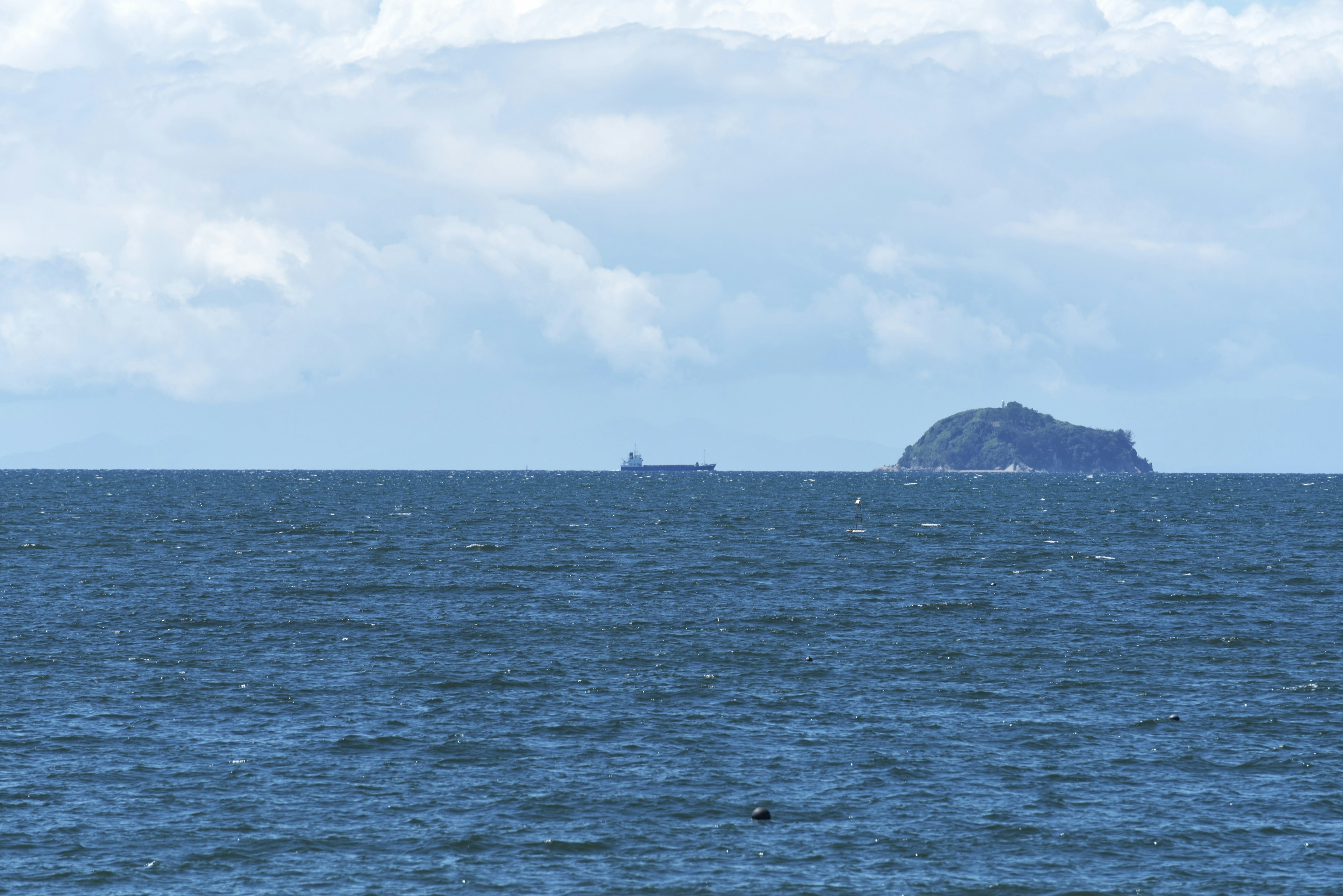 Isla en el océano con un barco a lo lejos