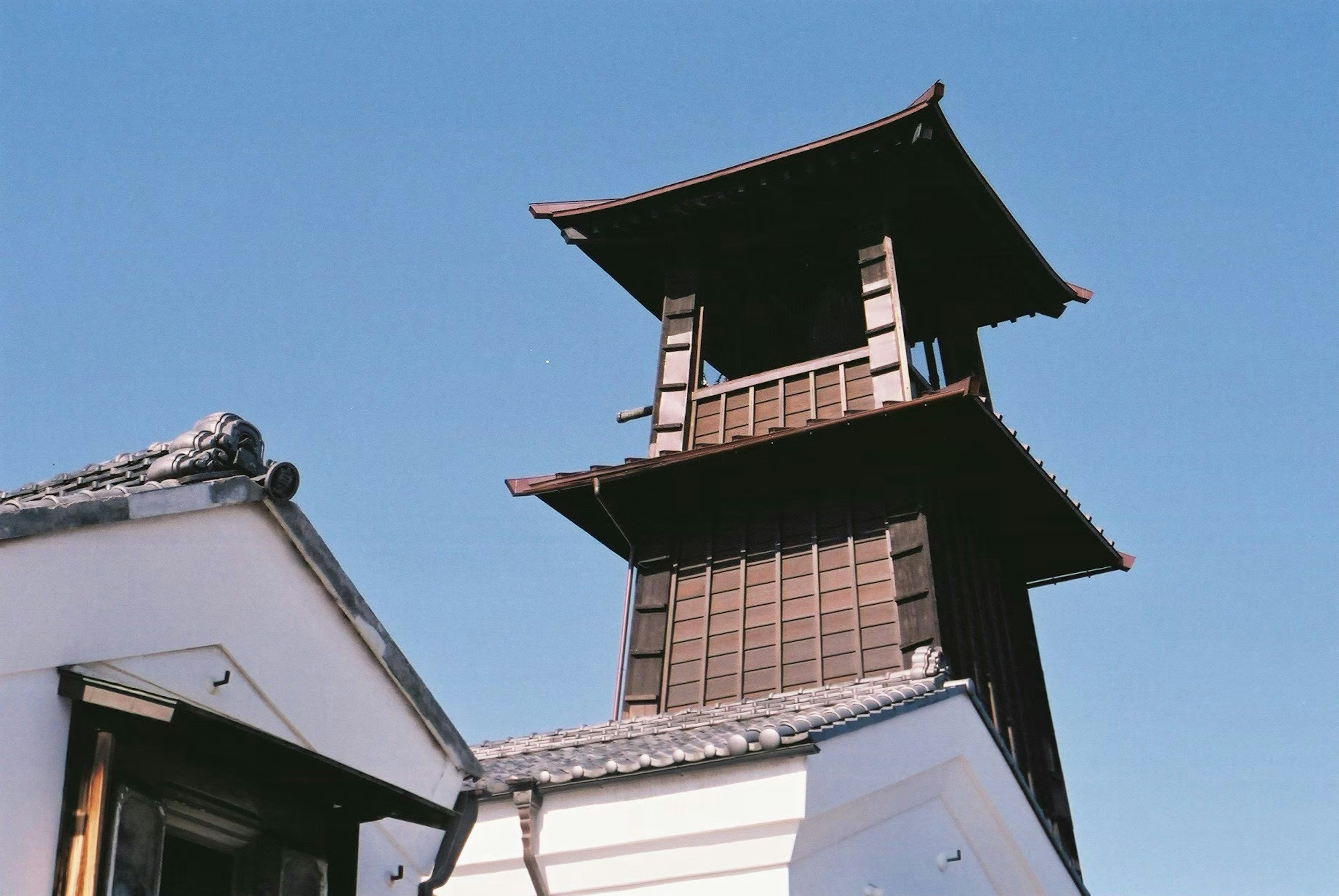 青空の下にある伝統的な日本の建物の鐘楼