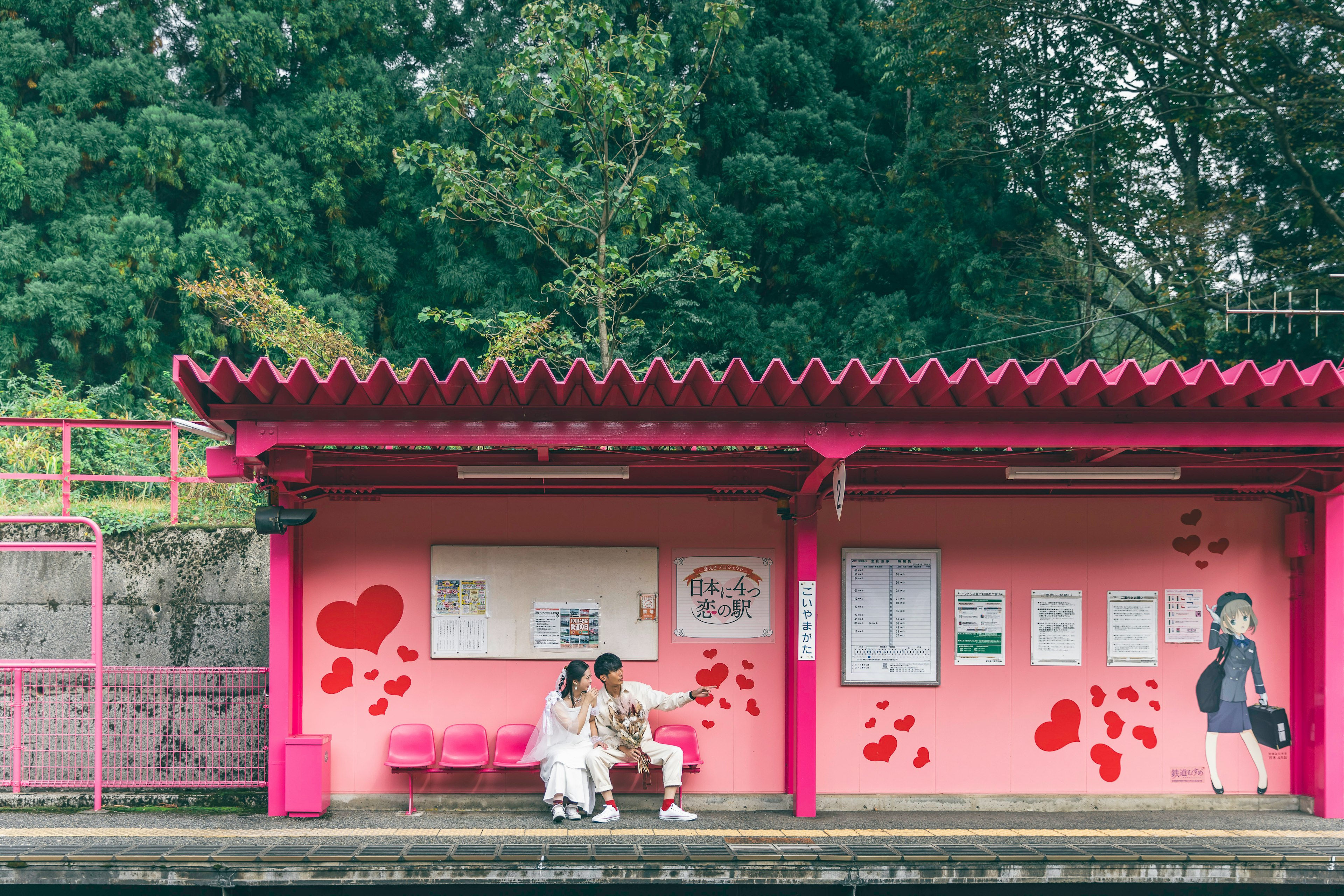 Couple sitting at a pink bus stop with heart decorations