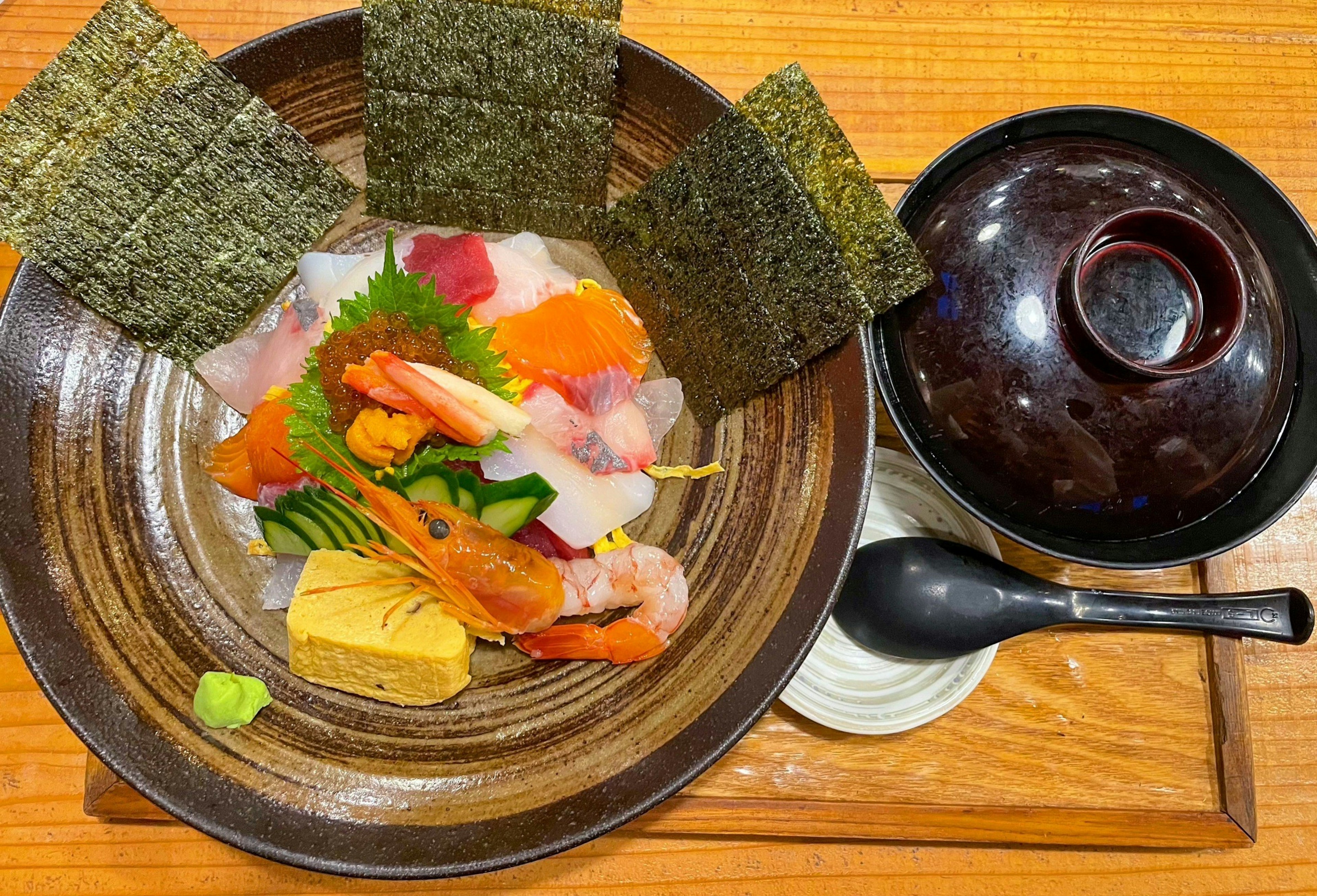 A plate of fresh sashimi and tamagoyaki with miso soup on the side