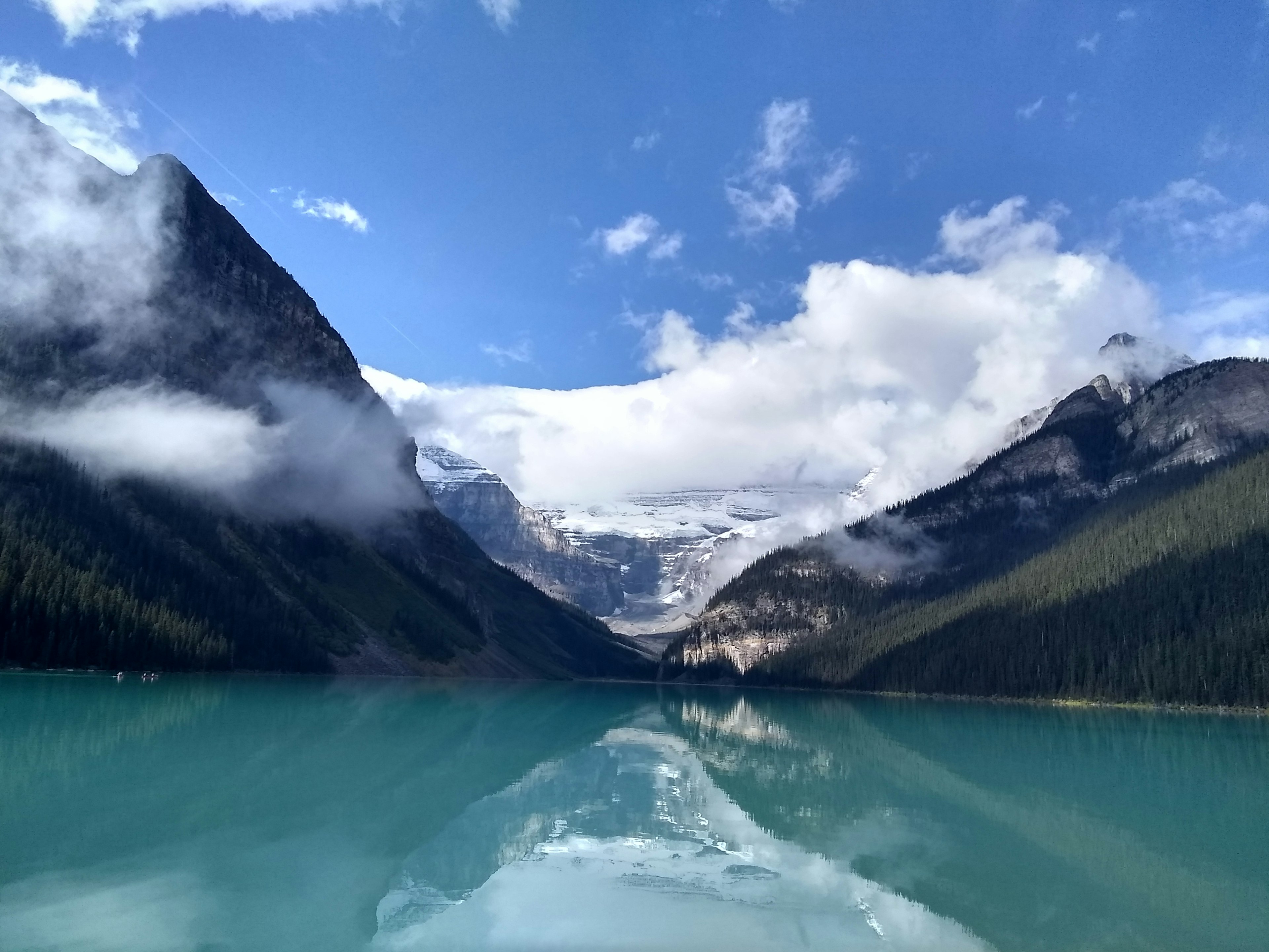 Vista panoramica di un lago turchese circondato da montagne e nuvole