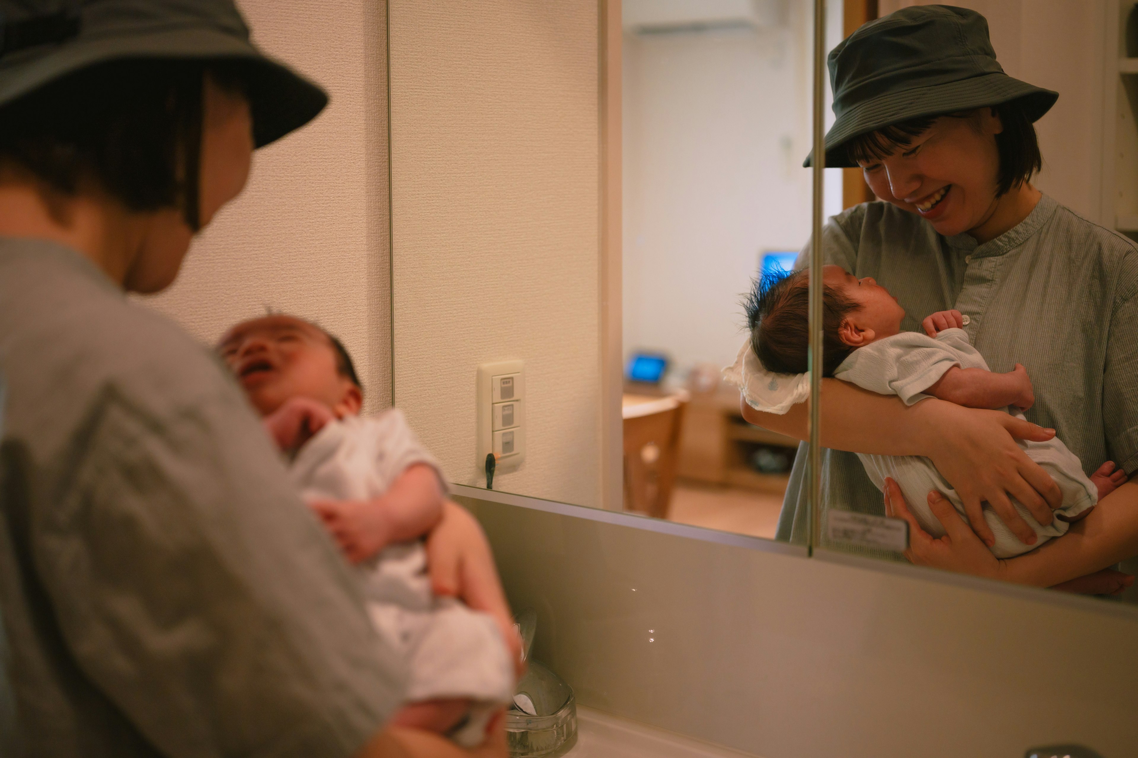Una madre che tiene un bambino davanti a uno specchio sorridendo al bambino