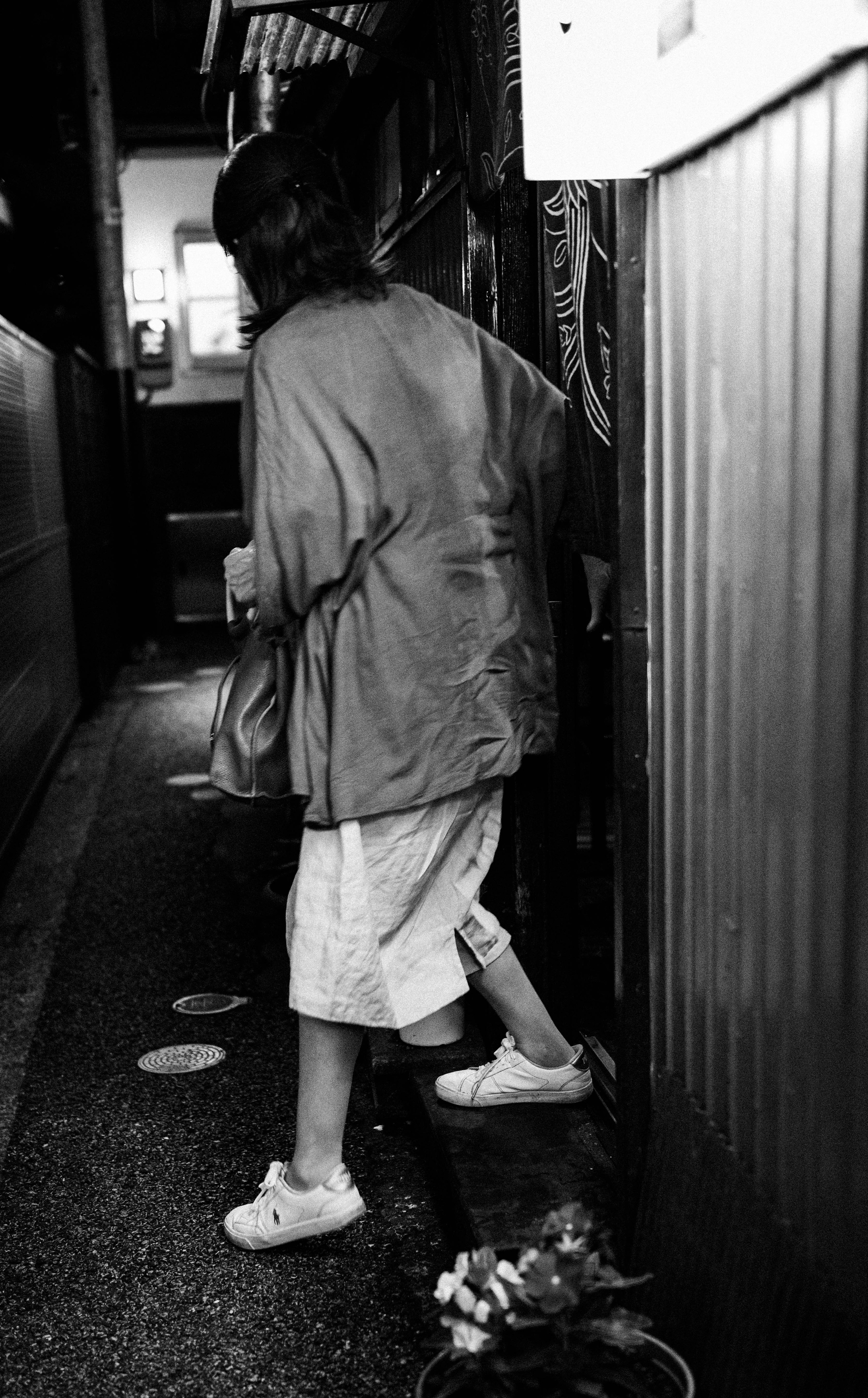 Una persona caminando en un callejón estrecho capturada en blanco y negro