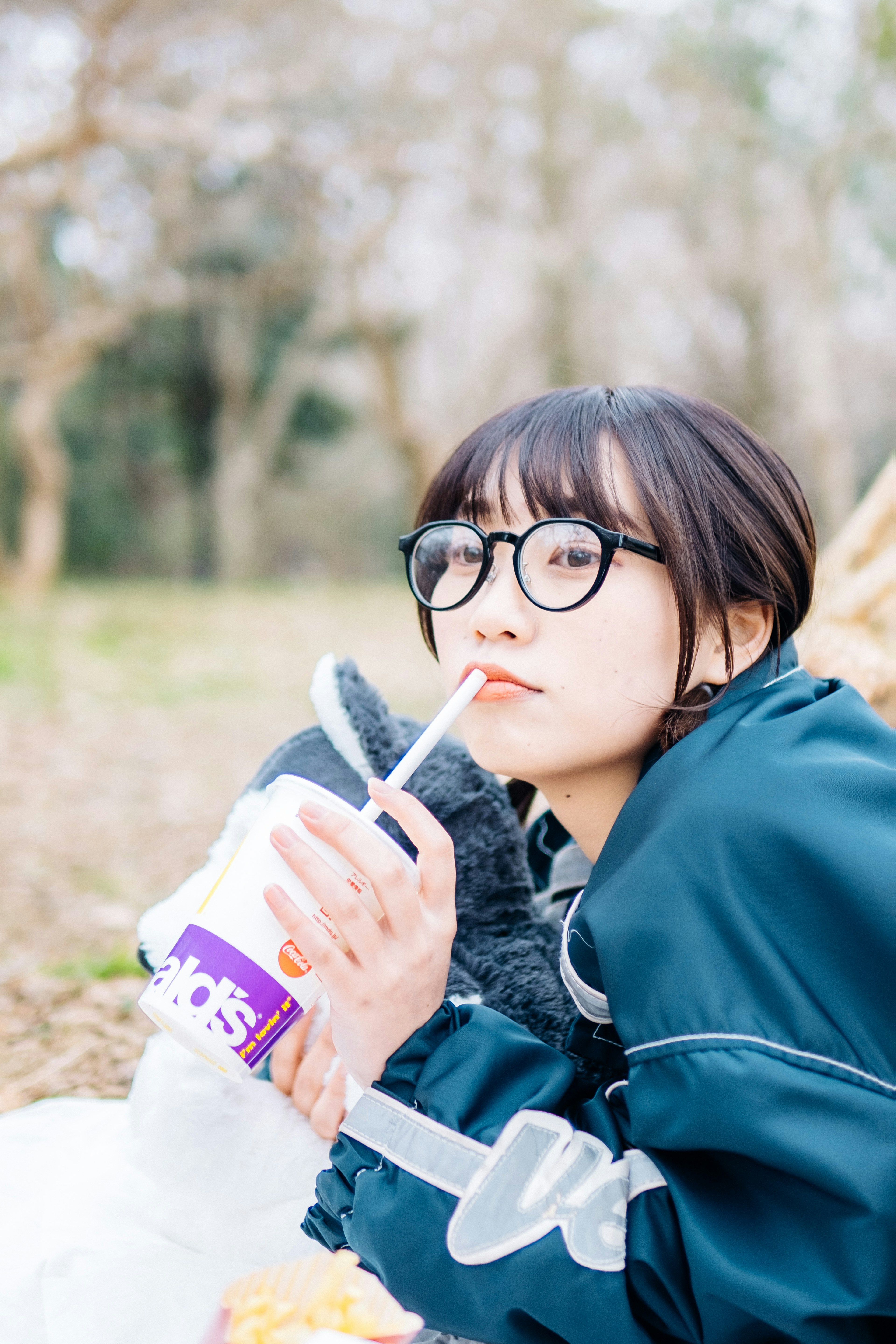 A woman relaxing in a park holding a drink