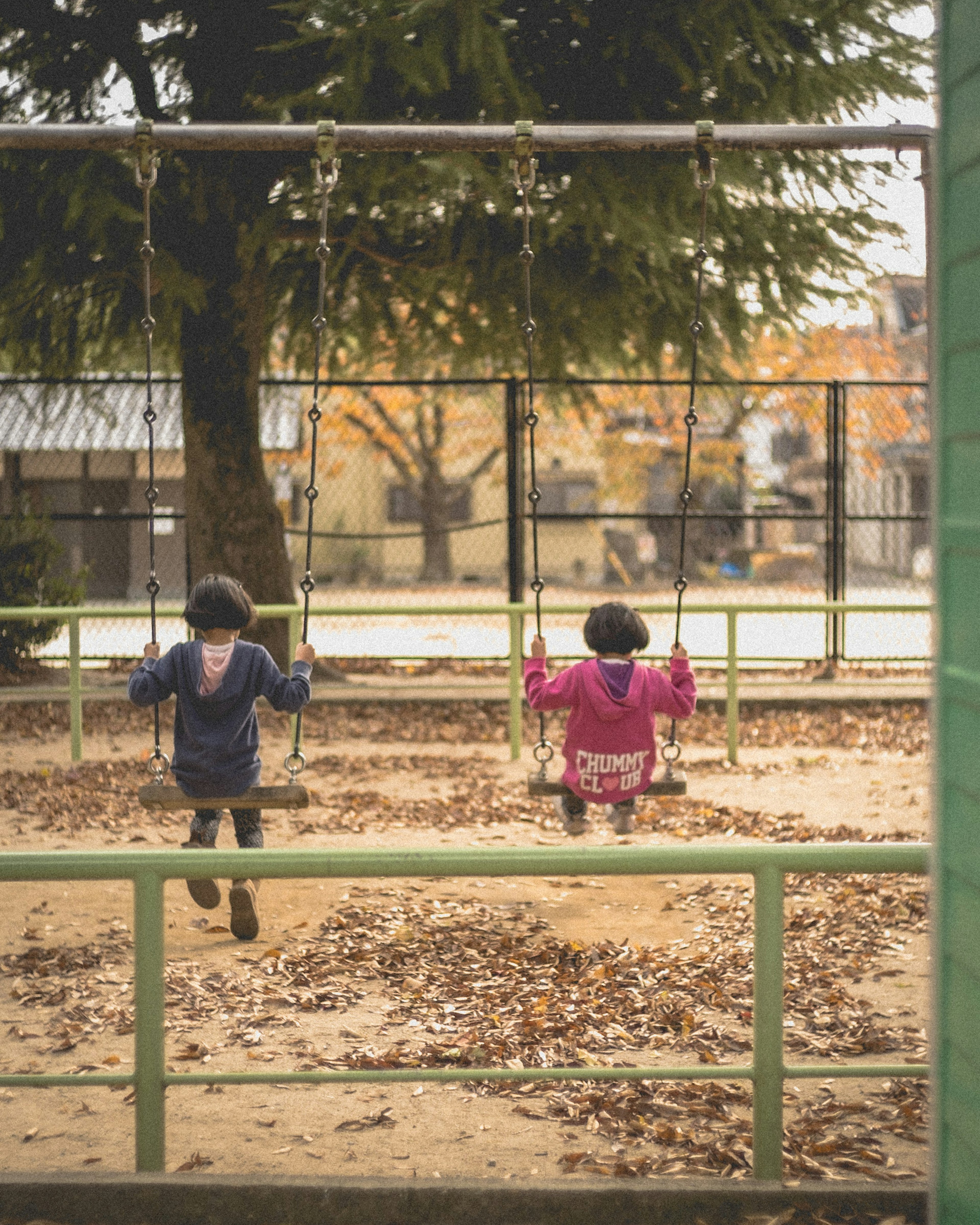 Two children playing on swings in a park