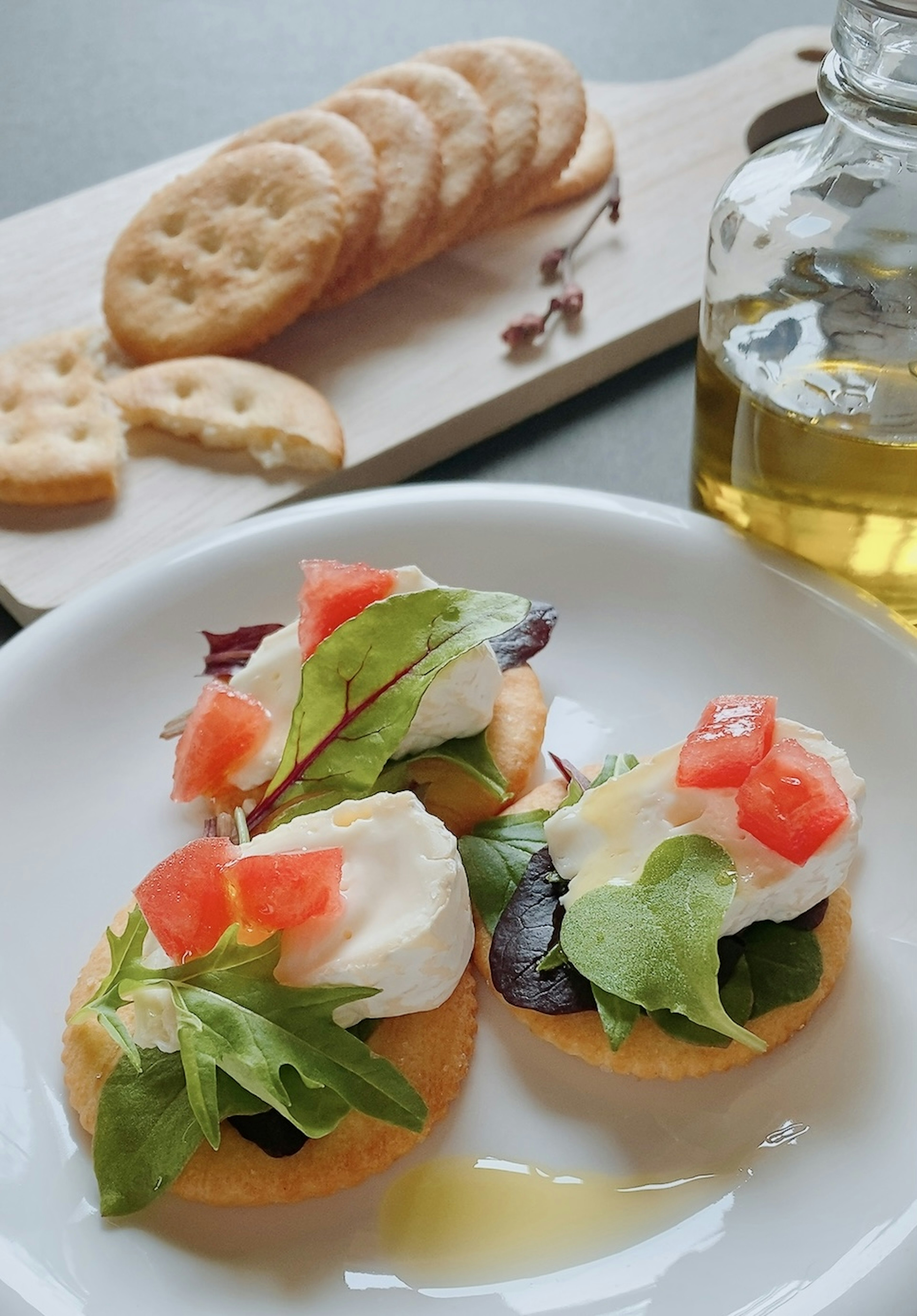 Antipasto con insalata e pomodori su un piatto bianco bottiglia d'olio d'oliva e cracker sullo sfondo