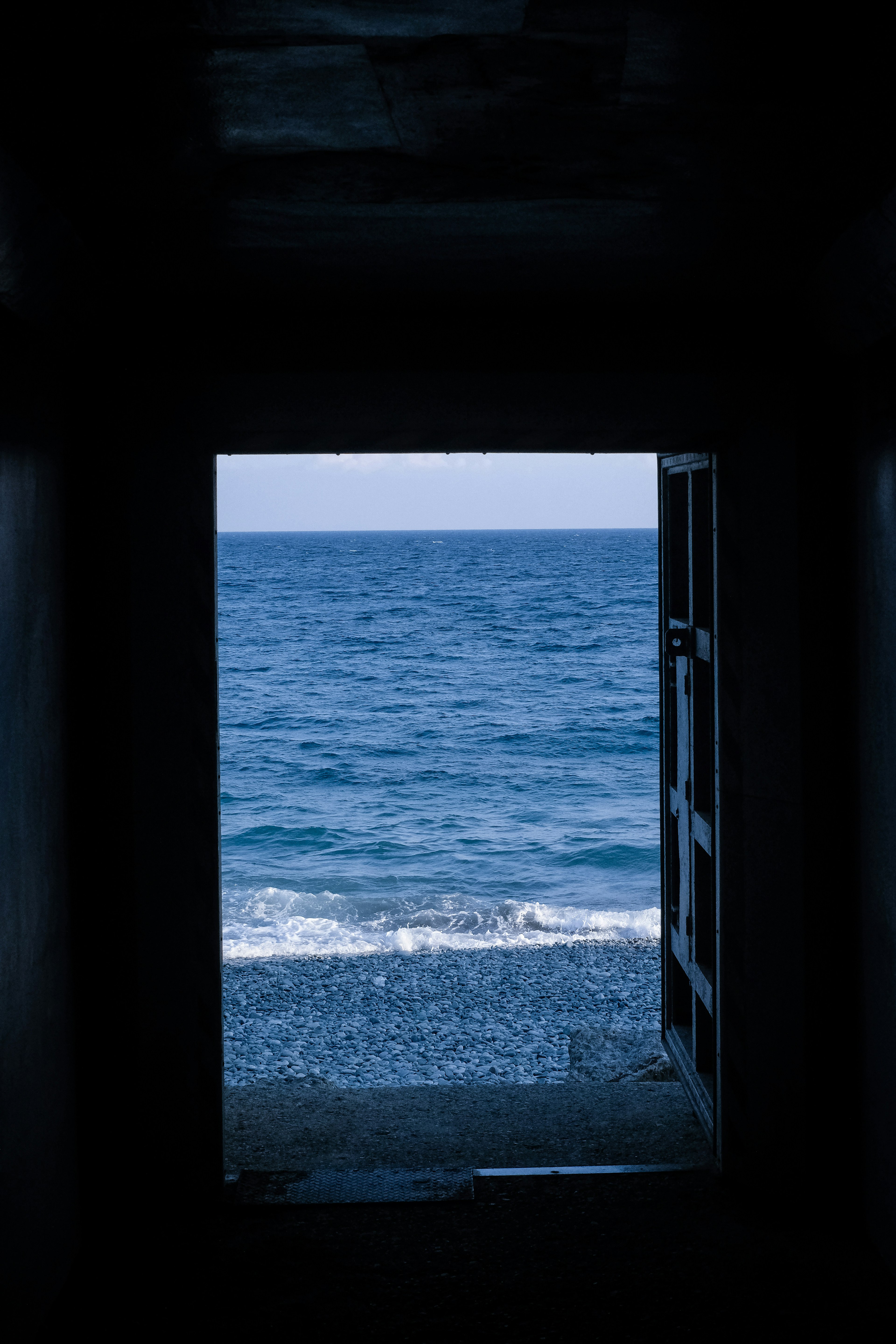 View of the sea through an open door with gentle waves